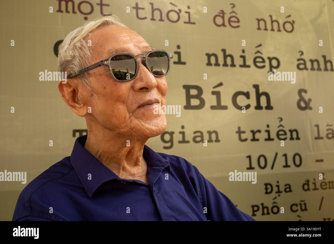 Un vietnamien âgé portant des lunettes de soleil visite une exposition de photographie à Hanoi, au Vietnam Banque D'Images