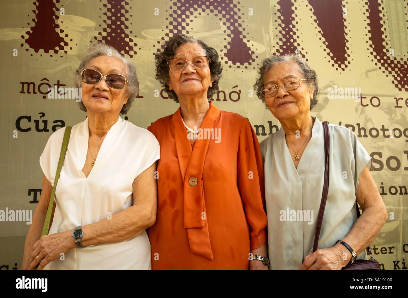 Trois sœurs vietnamiennes âgées visitant une exposition de photographie à Hanoi, Vietnam Banque D'Images