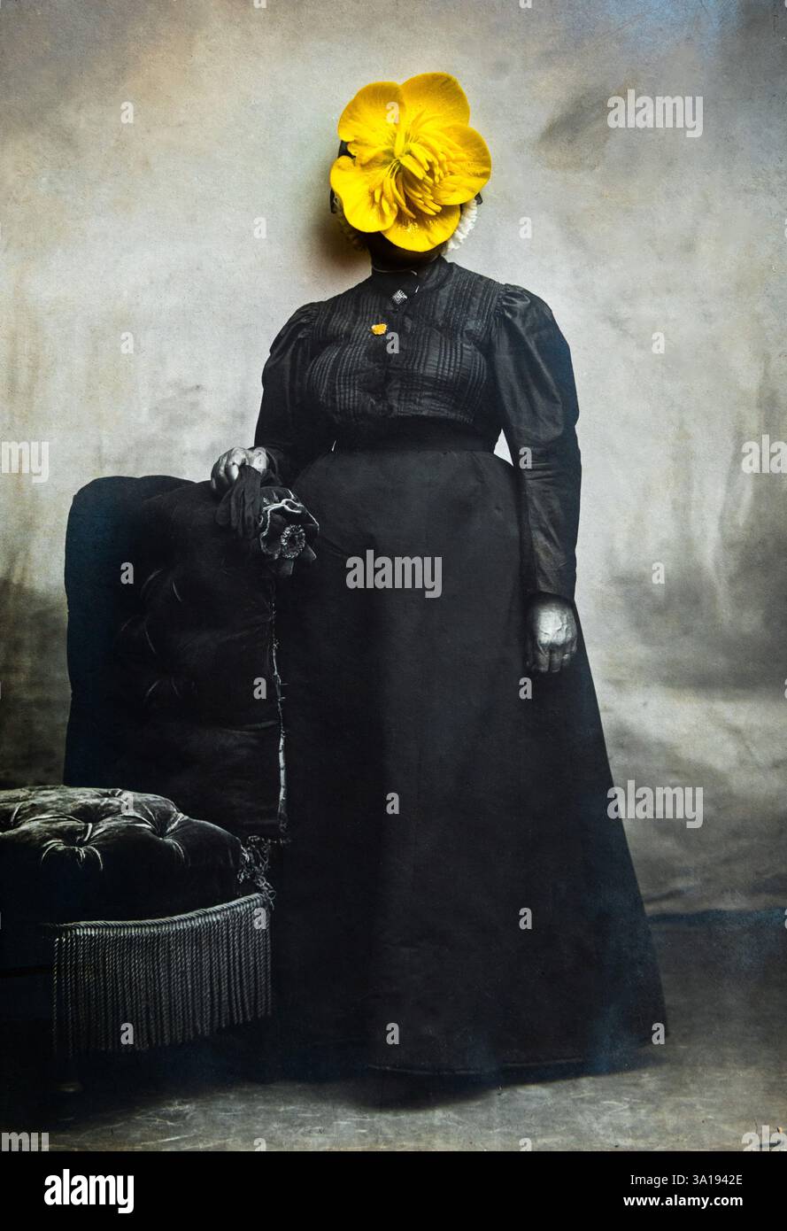 Un portrait vintage saisissant représente une femme dans une robe sombre, debout élégamment à côté d'une chaise ornée. Banque D'Images