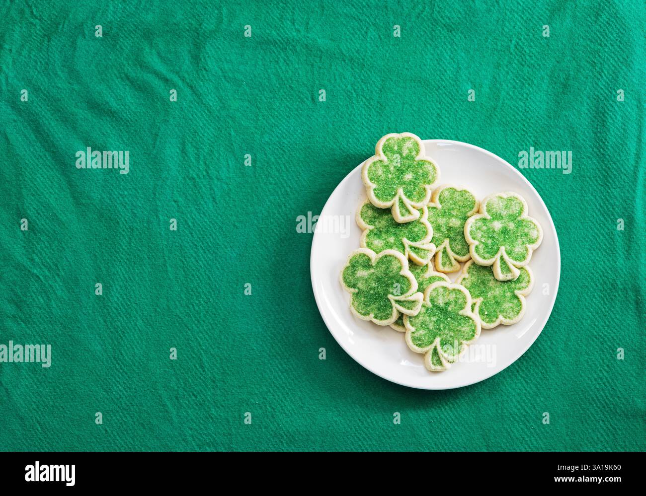 biscuits au sucre shamrock sur plaque blanche sur tissu vert plat posé par le haut Banque D'Images