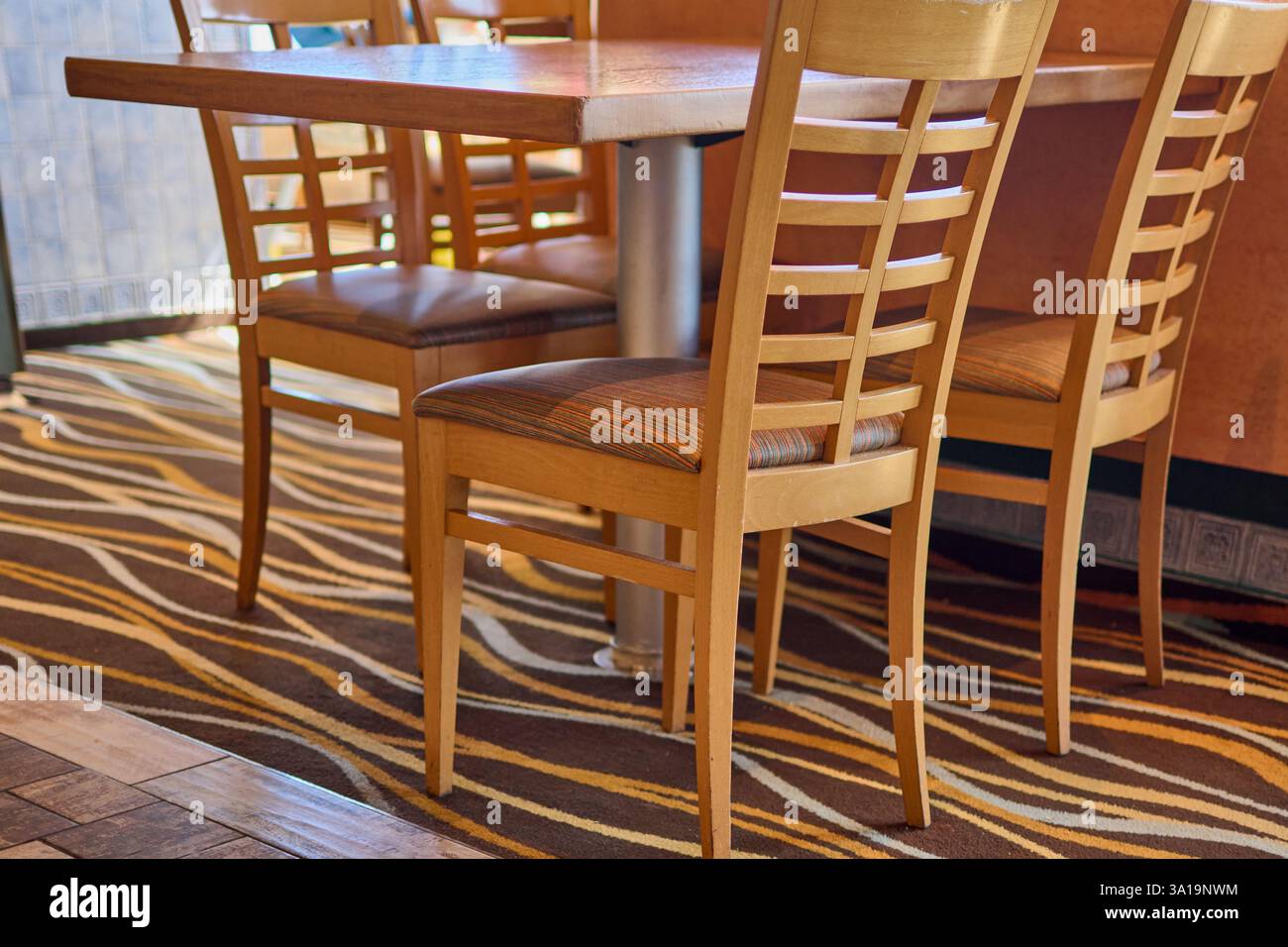 Intérieur chaleureux du restaurant avec chaises et tables en bois, décor vibrant et éclairage tamisé, créant une atmosphère accueillante idéale pour dîner. Banque D'Images