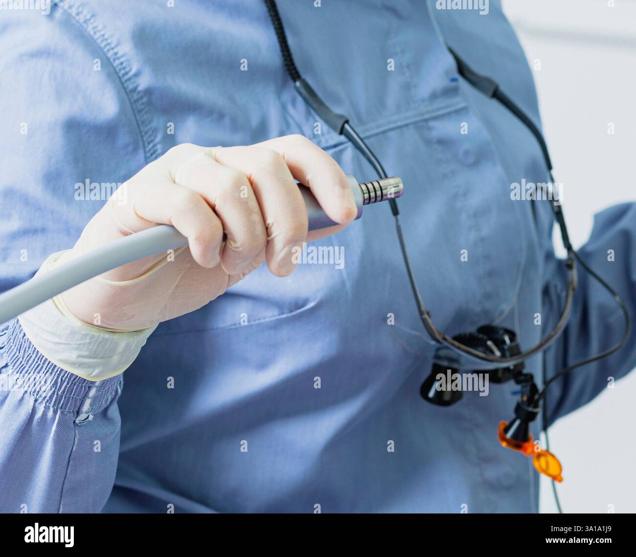 Dentiste portant des loupes chirurgicales et tenant une perceuse dentaire se préparant pour une intervention dentaire Banque D'Images
