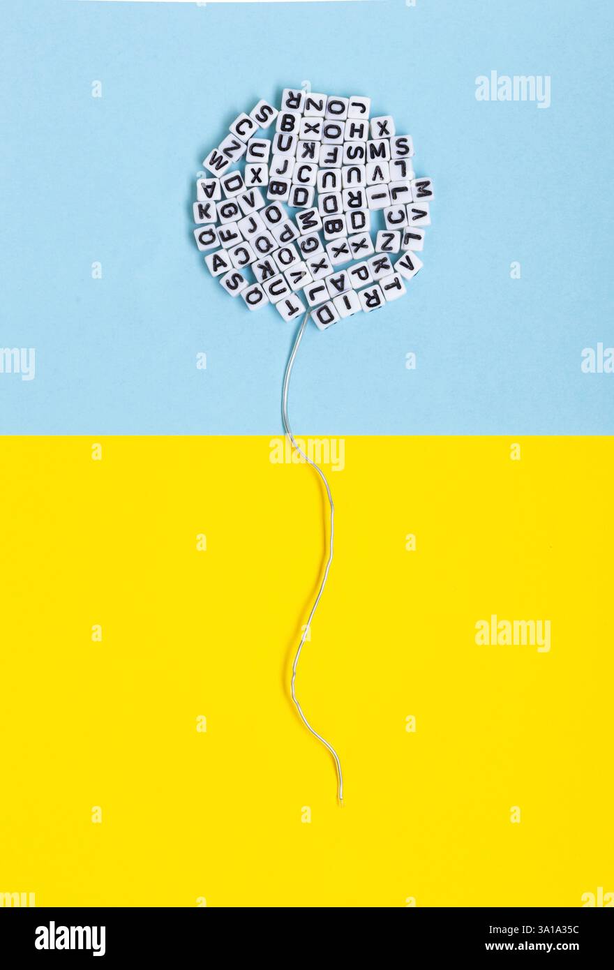 Bulle composée de lettres sur fond jaune et bleu. Image conceptuelle de la littérature, de la langue et de la liberté d'expression. Banque D'Images