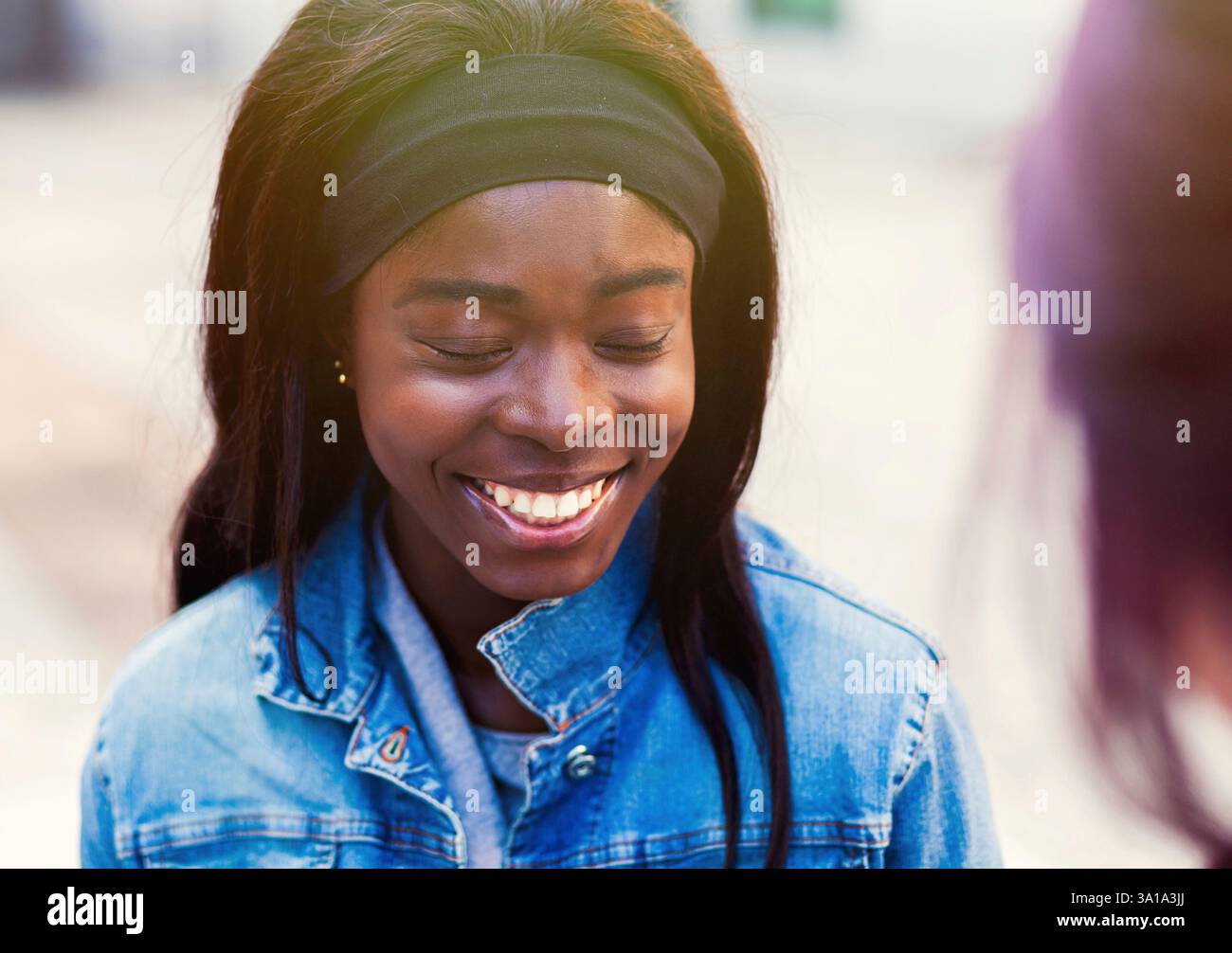 Deux amis, de race blanche et de l'Afrique de l'appartenance ethnique, de parler assis sur un banc à l'extérieur. Banque D'Images