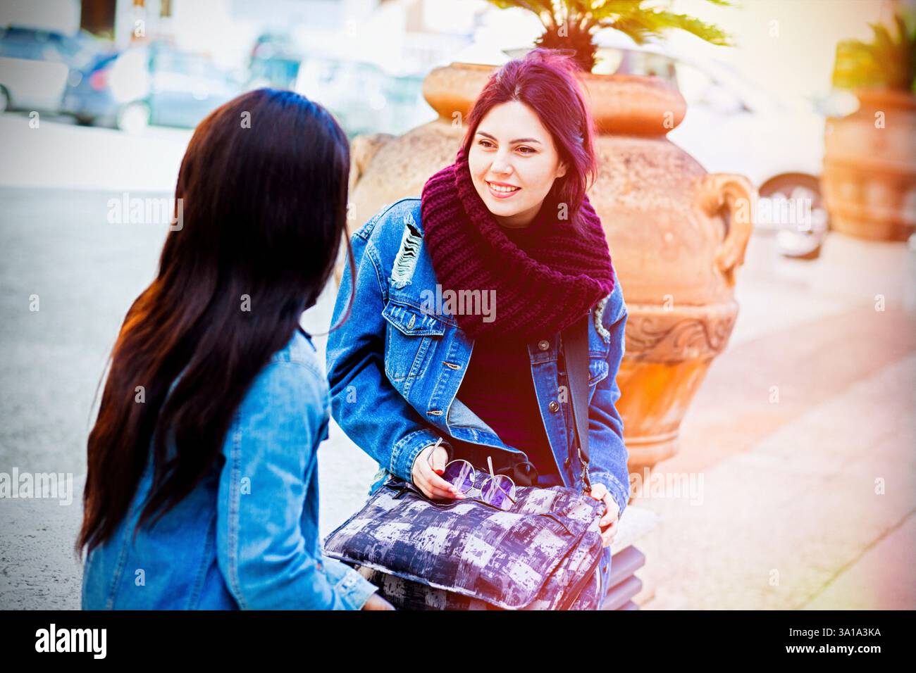 Deux amis, de race blanche et de l'Afrique de l'appartenance ethnique, de parler assis sur un banc à l'extérieur. Banque D'Images