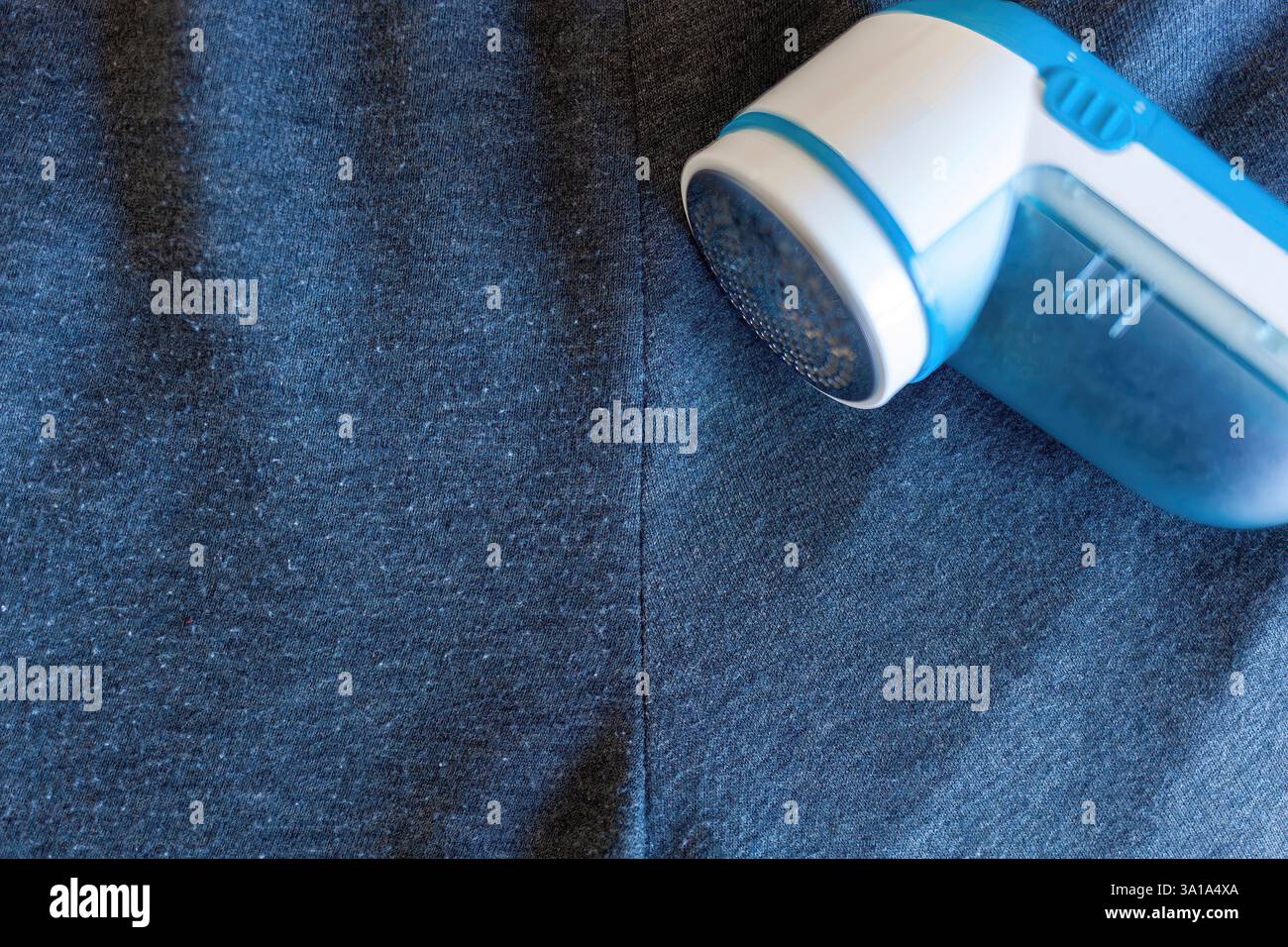Rasoir en tissu moderne sur tissu gris. Cet appareil permet d'éliminer les peluches des vêtements. Banque D'Images