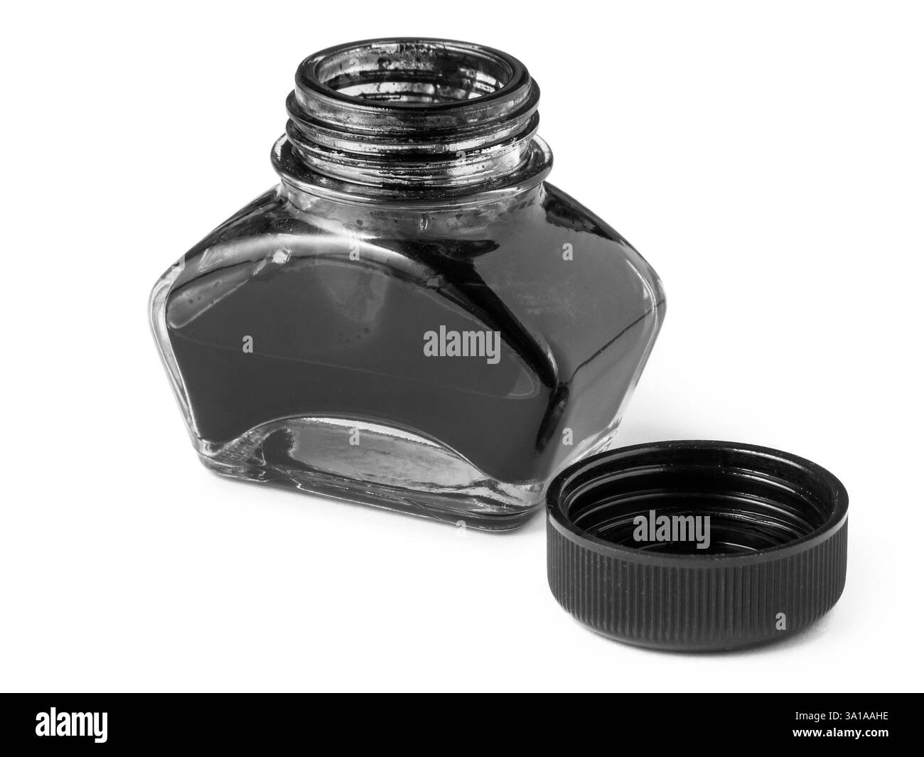 Vue rapprochée surélevée d'un encrier ouvert avec un bouchon à vis placé à côté isolé sur blanc avec des ombres claires en monochrome. Banque D'Images