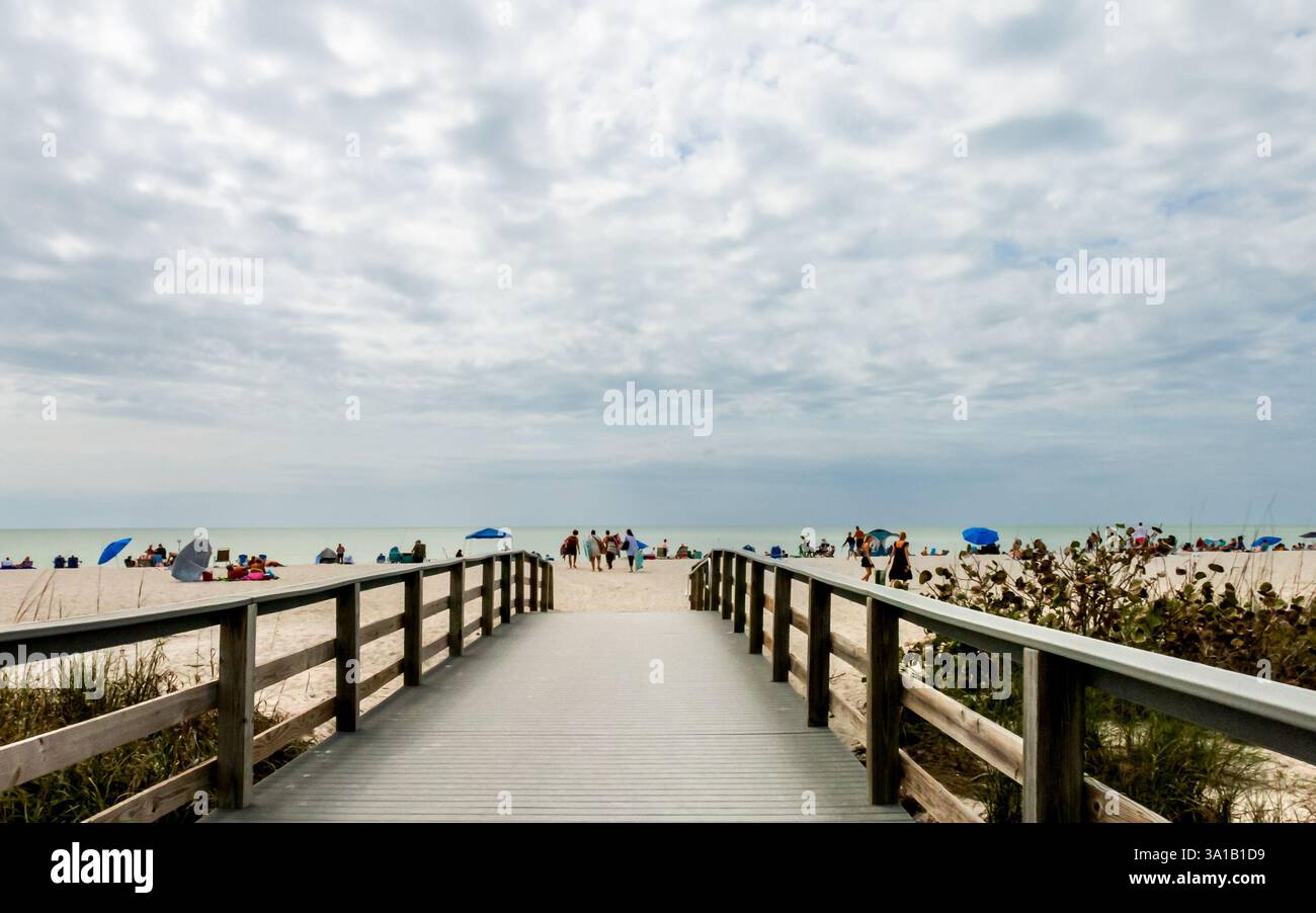 2/22/2025 Sanibel Island, FL, États-Unis : un pont en bois avec garde-corps guide les amateurs de plage à Bowman's Beach sur Sanibel Island, FL. Un ciel nuageux dramatique co Banque D'Images