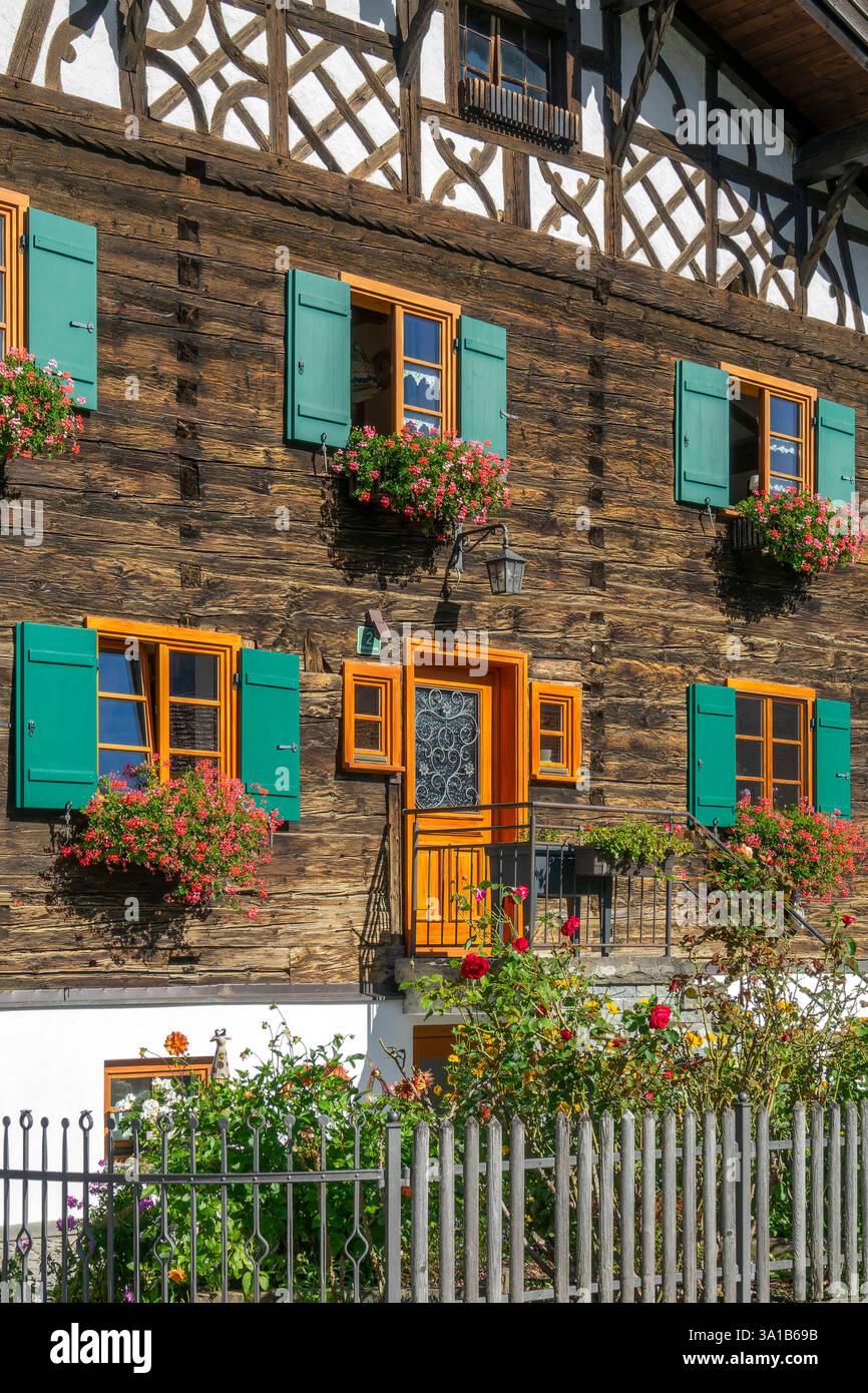 Rettenberg, Gästehaus Stork, vieille maison en bois avec pignon à colombages, fleurs devant les fenêtres et volets verts. Banque D'Images