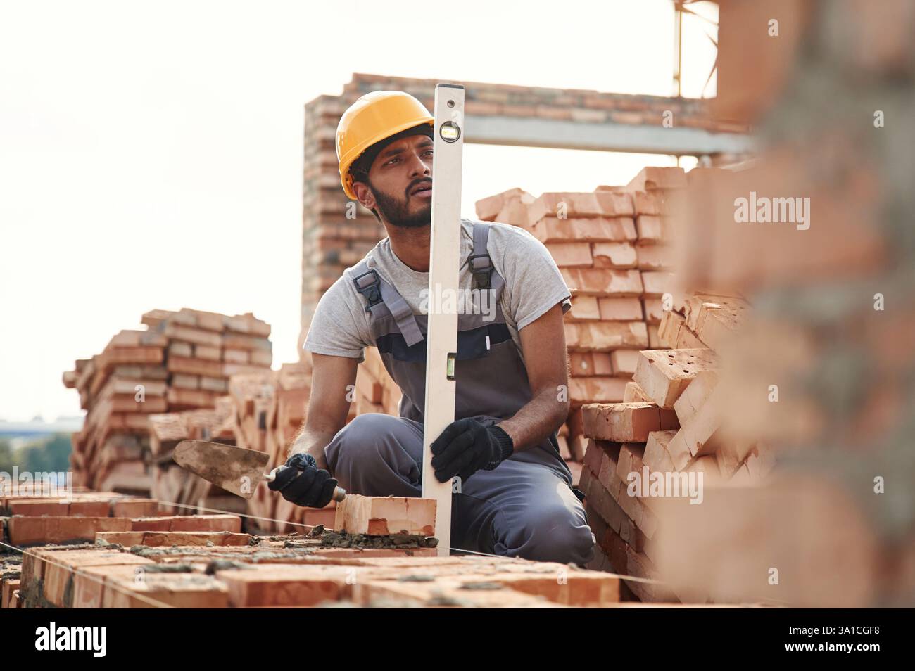 Utilisation du niveleur. Bel homme indien est sur le chantier de construction. Banque D'Images