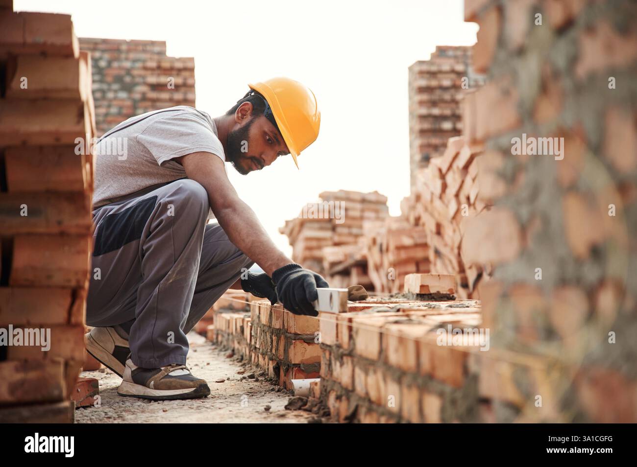 Utilisation du niveleur. Bel homme indien est sur le chantier de construction. Banque D'Images