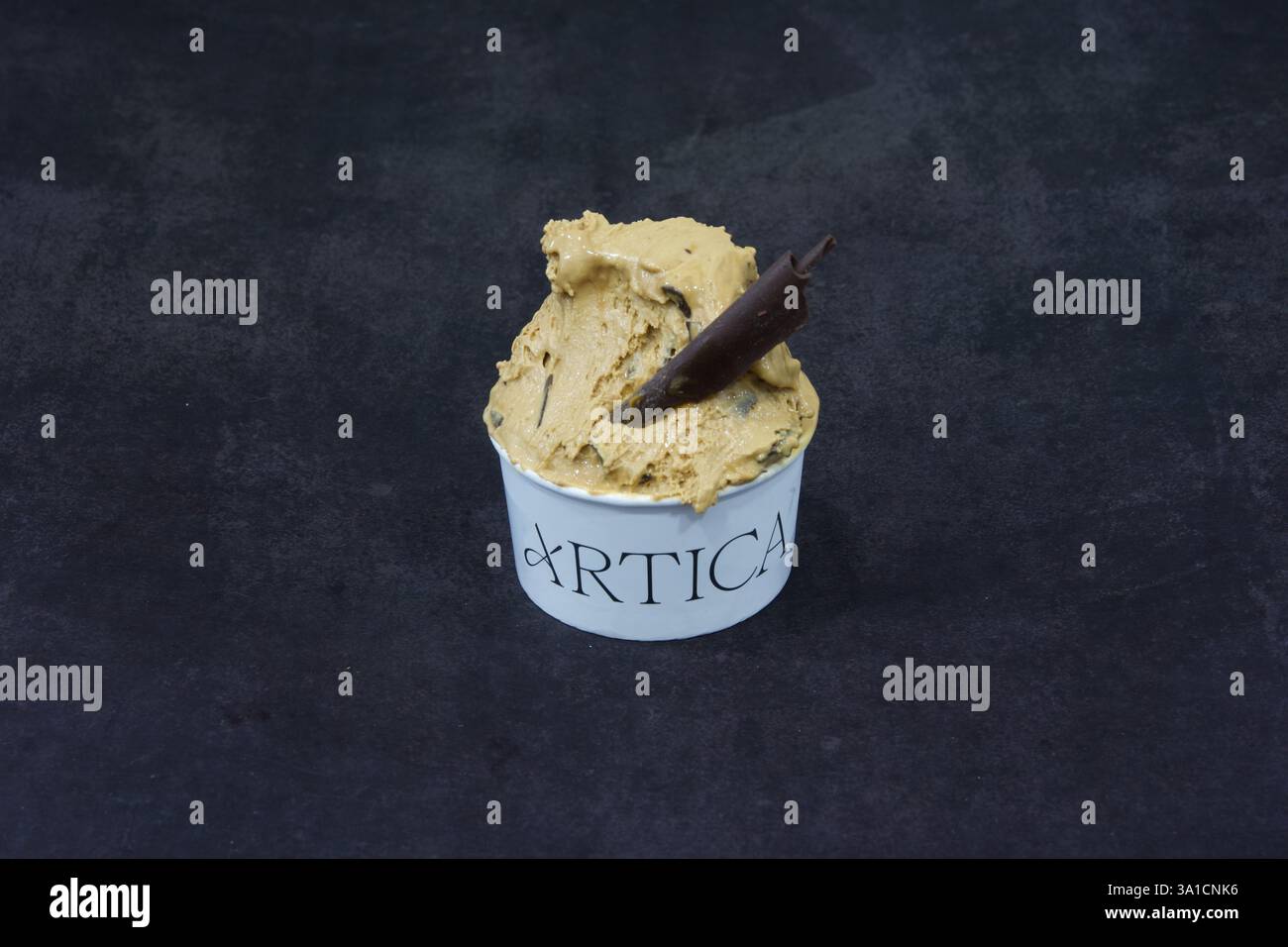 Une boule de crème glacée avec un bâton de chocolat dedans. La crème glacée est dans un bol blanc avec le mot Artica écrit dessus Banque D'Images