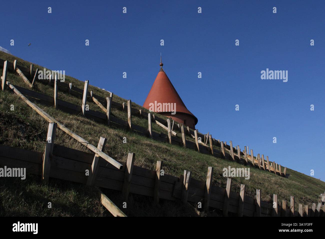 Vieille tour en briques rouges dans la ville européenne buder le ciel bleu clair au printemps, la lumière du soleil, la structure de construction du moyen âge, la construction militaire, la pyramide Banque D'Images