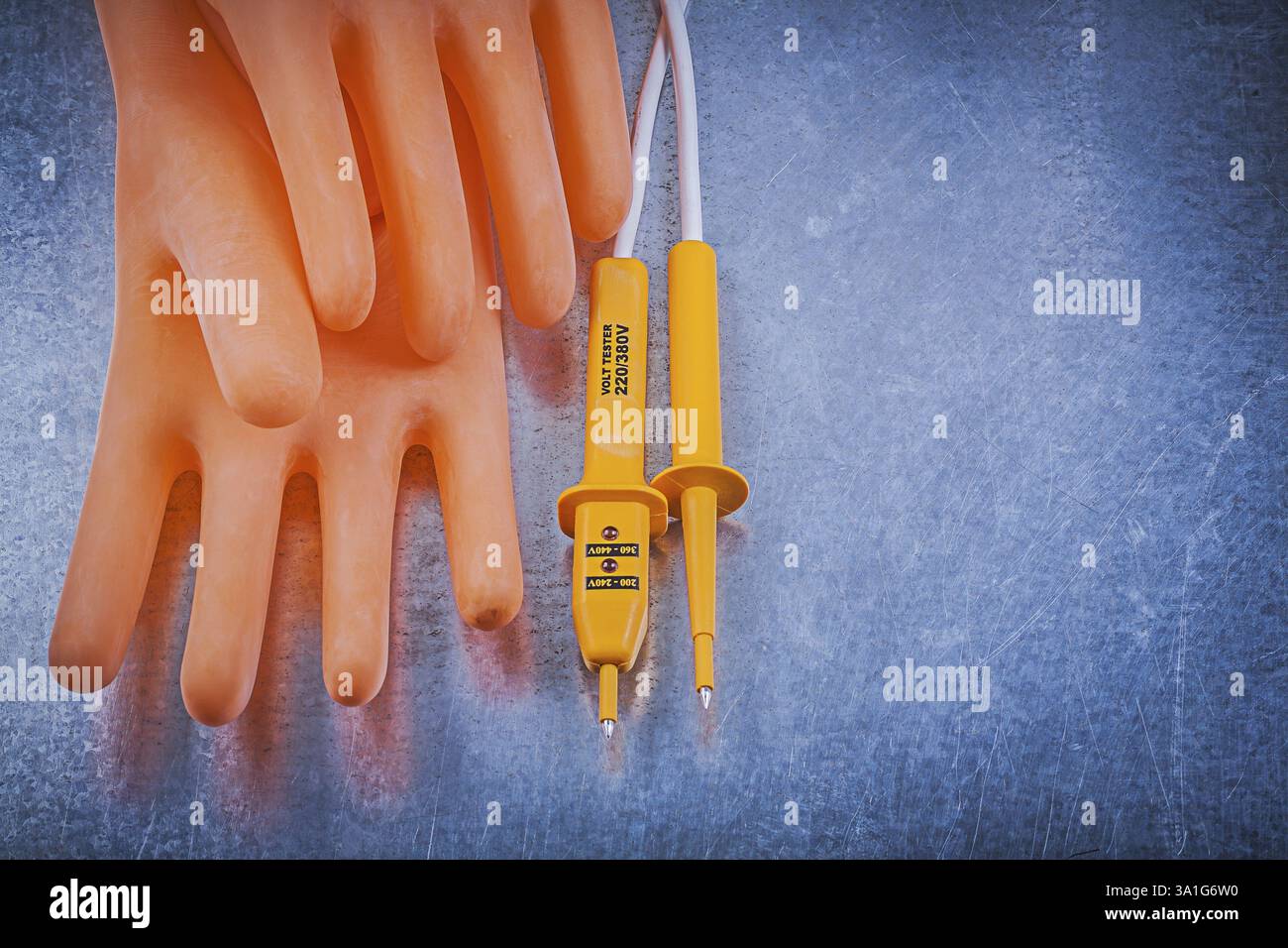 Testeur électrique de gants en caoutchouc isolant sur le concept d'électricité de fond métallique Banque D'Images