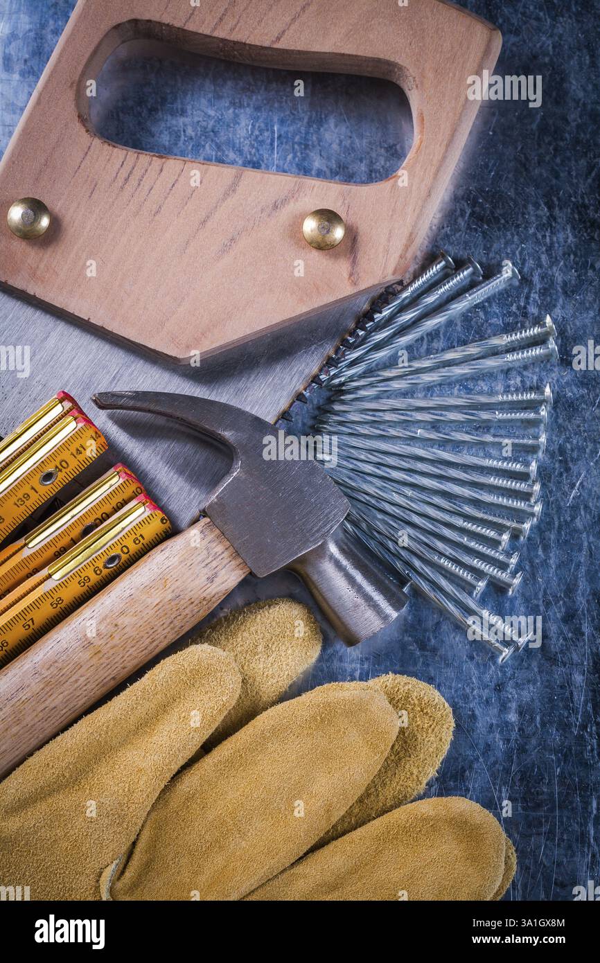 Gants de protection pour scie à main construction clous mètre en bois et marteau à griffe sur fond métallique rayé gros plan vue concept de construction Banque D'Images