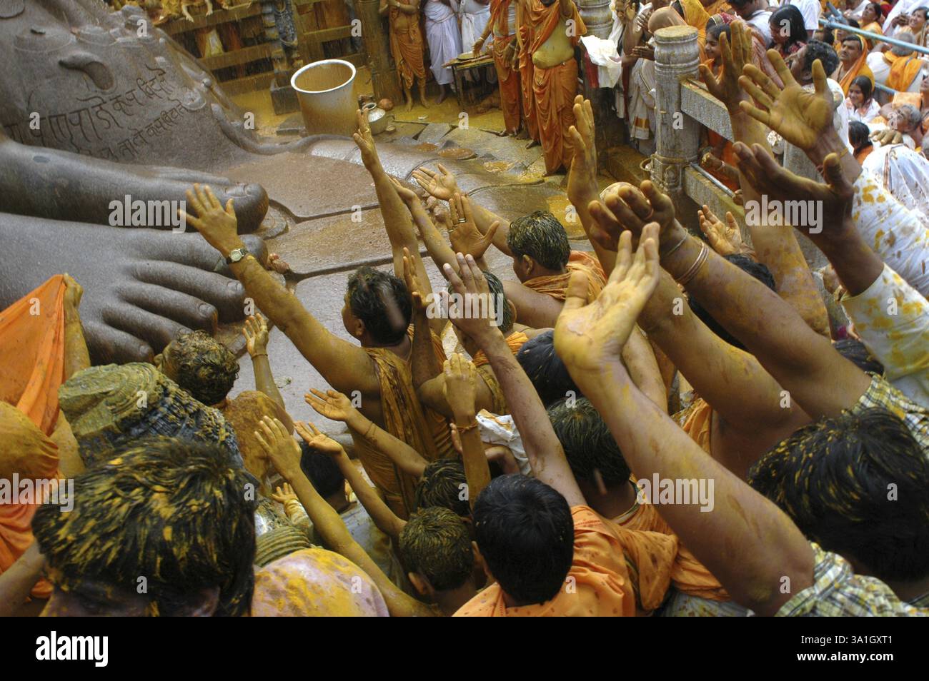 Les dévots debout au pied de la statue monolithique de 58,8 pieds de jaïn saint Gomateshwara seigneur Bahubali dans Mahamastakabhisheka cérémonie d'onction de tête, Srav Banque D'Images