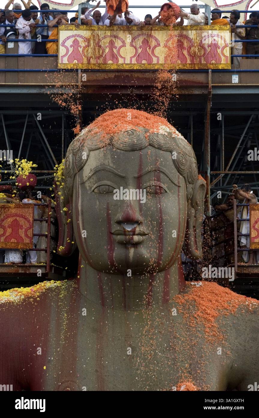 Dévots douchant des fleurs sur la statue monolithique de 58,8 pieds de jaïn saint Gomateshwara seigneur Bahubali couvert de vermillon dans Mahamastakabhisheka tête A. Banque D'Images