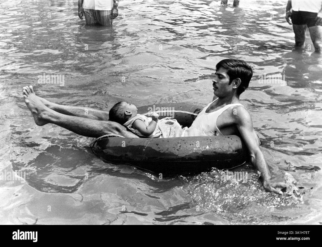 Homme flottant sur l'eau avec son bébé, Inde, Asie Banque D'Images