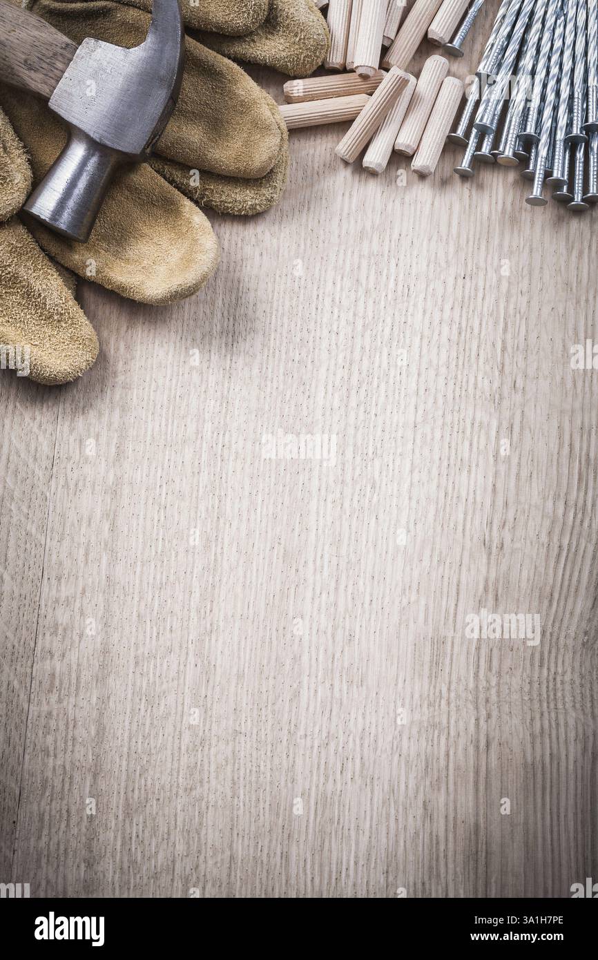 Tas de chevilles en bois griffes marteau gants de travail en cuir et clous inoxydables sur le concept de construction de vue de dessus de planche de bois Banque D'Images