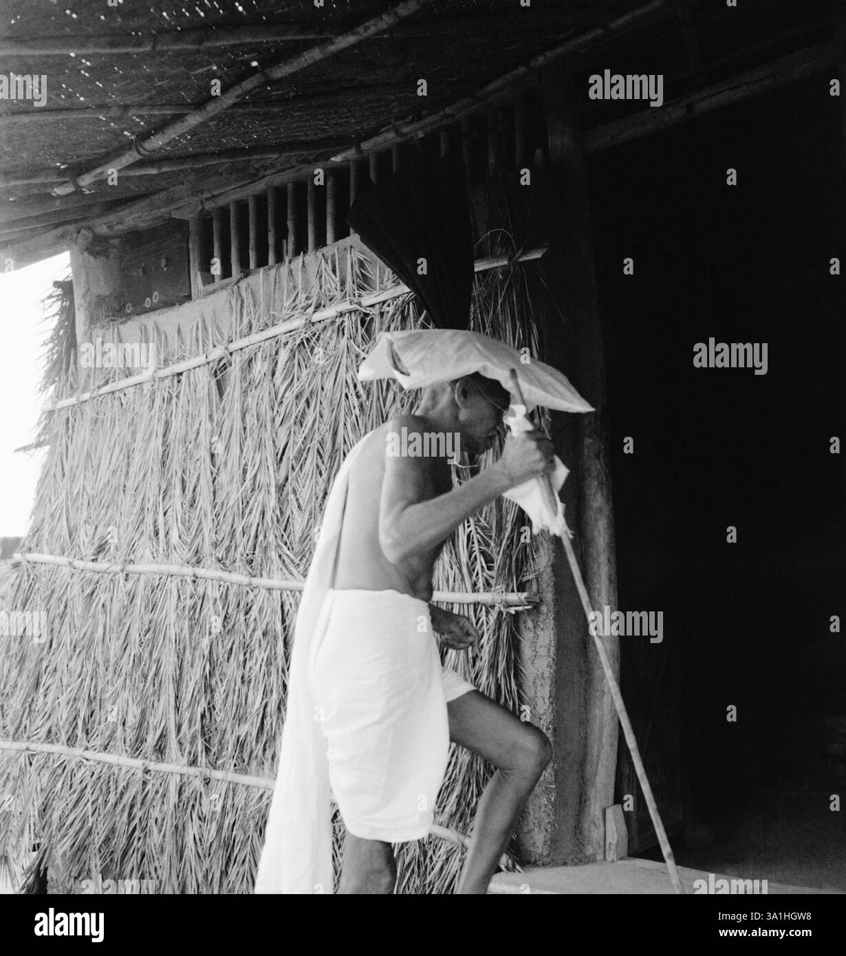 Mahatma Gandhi, portant un sac de boue sur sa tête, entrant dans une cabane à Sevagram Ashram, 1941 NO MR Banque D'Images