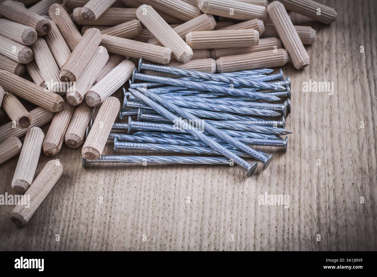 Tas de chevilles en bois et de clous de construction sur fond en bois Banque D'Images