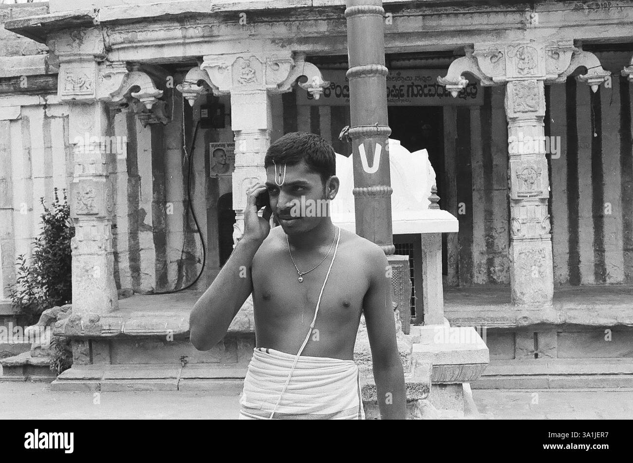 Homme parlant sur mobile devant le temple, village de Hemmaragala près de Nanjangud dans le district de Mysore, Karnataka, Inde, Asie Banque D'Images