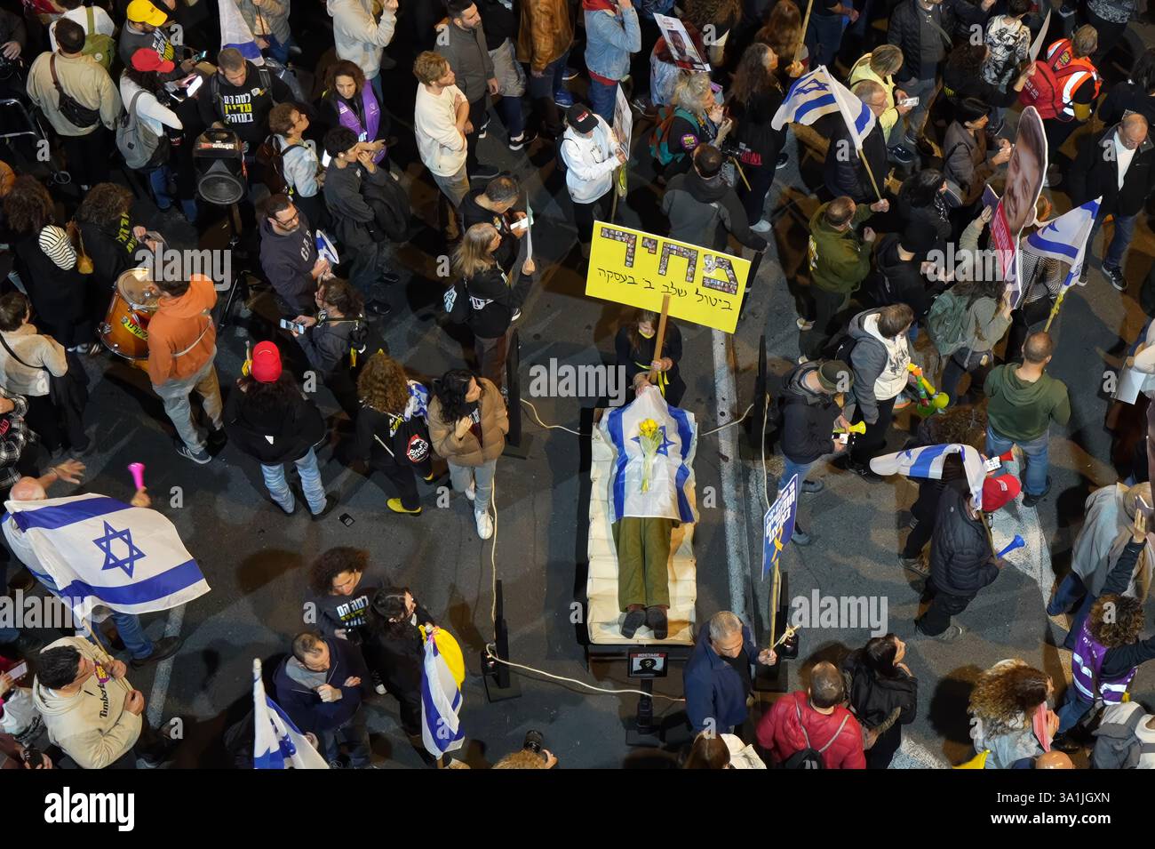 TEL AVIV, ISRAËL - 8 MARS : des manifestants tiennent des drapeaux israéliens autour d'un mannequin représentant un cadavre couvert d'un drapeau lors d'une manifestation de masse devant le siège du ministère de la Défense appelant à la conclusion de l'accord de cessez-le-feu avec le Hamas et exigeant la libération des otages restants détenus dans la bande de Gaza le 8 mars 2025 à tel Aviv, en Israël. Banque D'Images