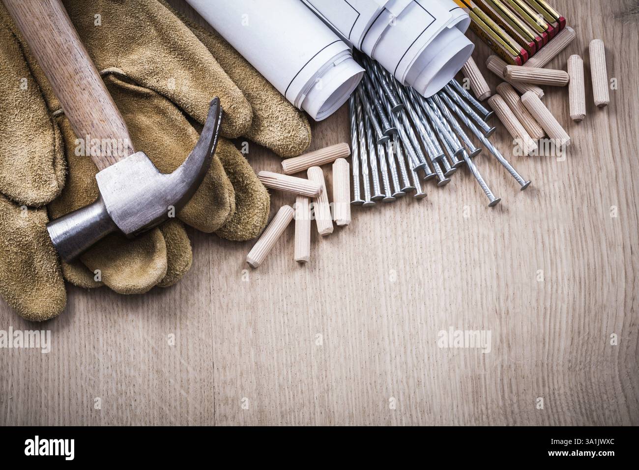 Version horizontale des chevilles de compteur en bois plans de construction griffe marteau gants de protection en cuir et clous en métal sur le concept de maintenance de planche de bois Banque D'Images