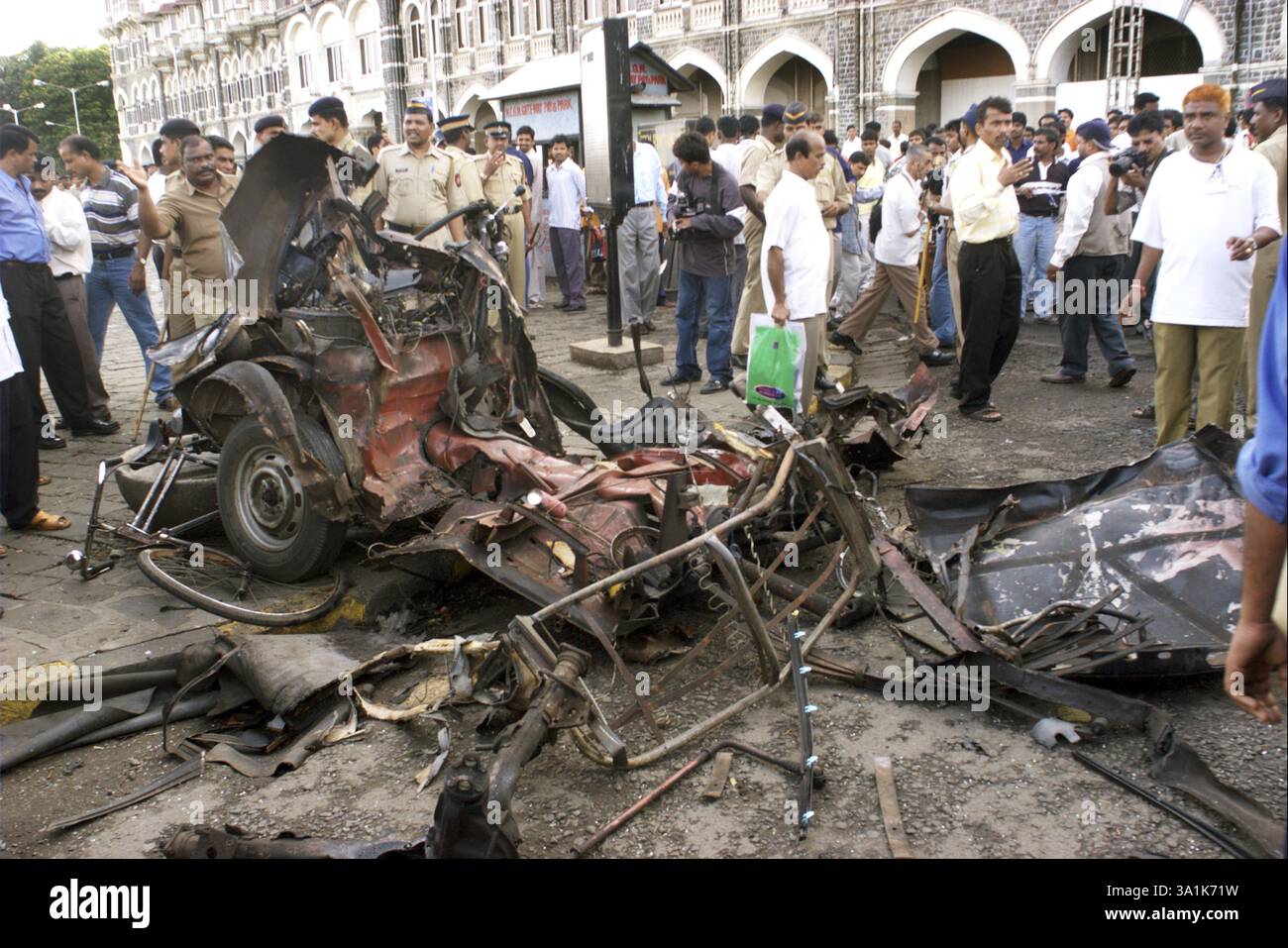 Les gens regardent des restes de taxi endommagés par de puissants explosifs stationnés sur le parking près de Gateway of India, Bombay Mumbai, Maharashtra, Inde sur au Banque D'Images