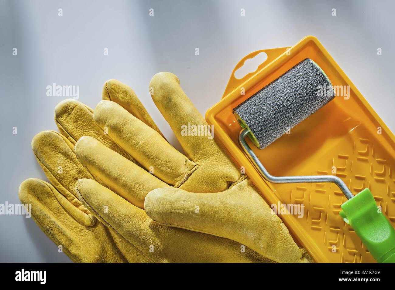 Gants de sécurité en cuir rouleau de bac à peinture sur la surface blanche Banque D'Images