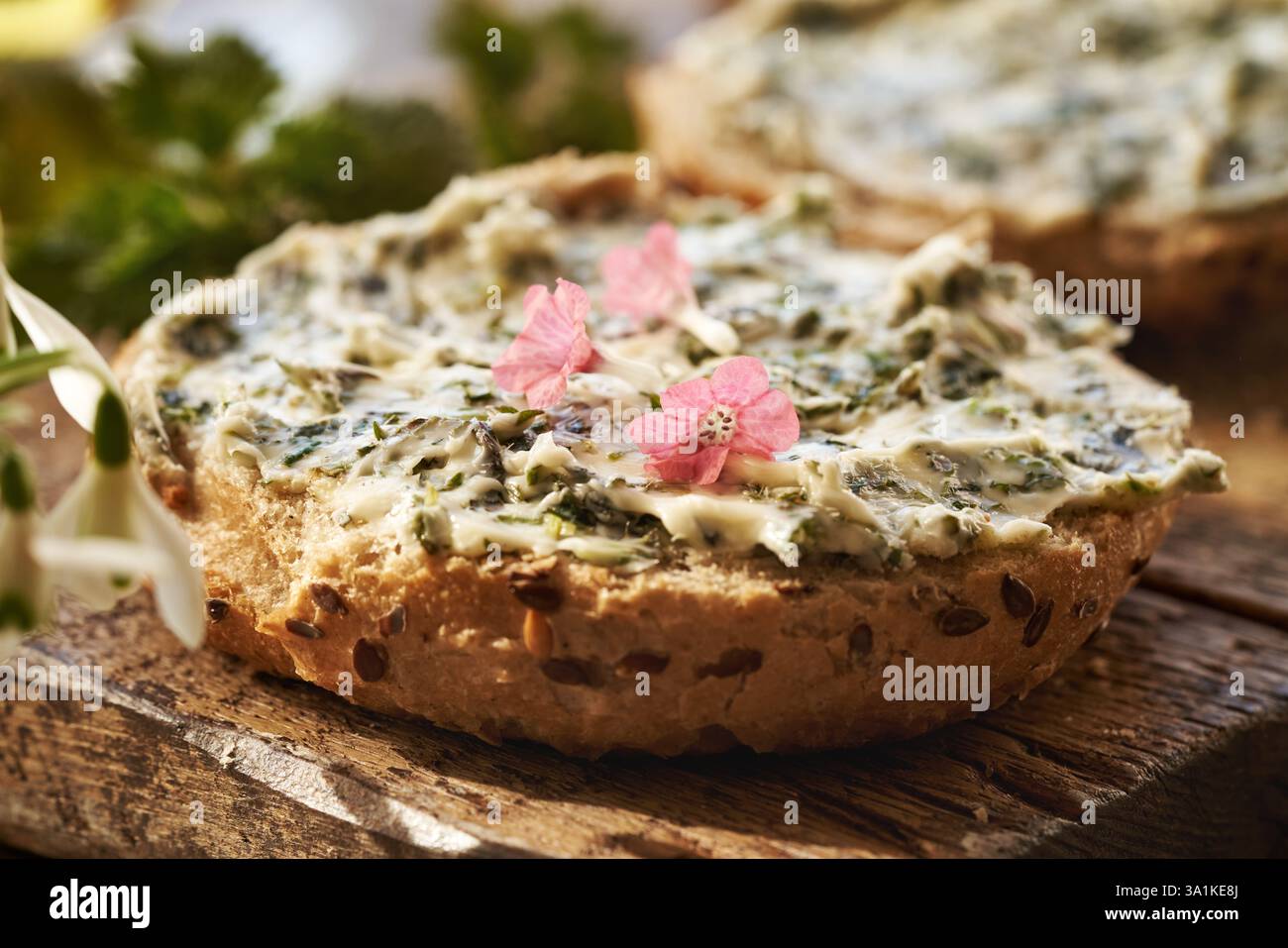 Un poux de pain avec du beurre d'ortie et des fleurs fraîches d'armoise poumon ramassé au début du printemps Banque D'Images