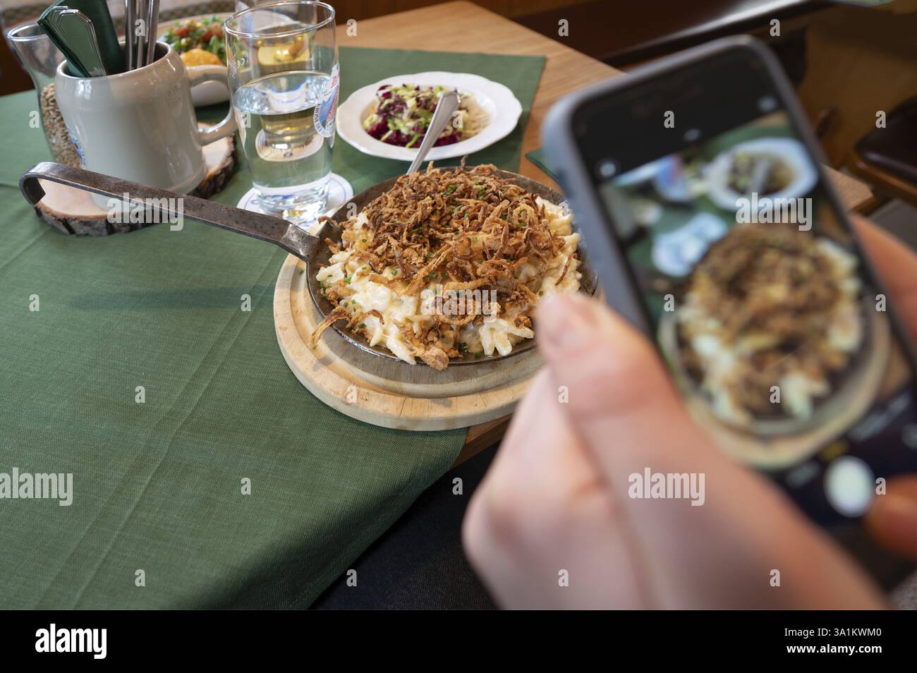Invité prenant des photos de sa nourriture avec son téléphone portable, fromage spaetzle dans une casserole, Bavière, Allemagne, Europe Banque D'Images