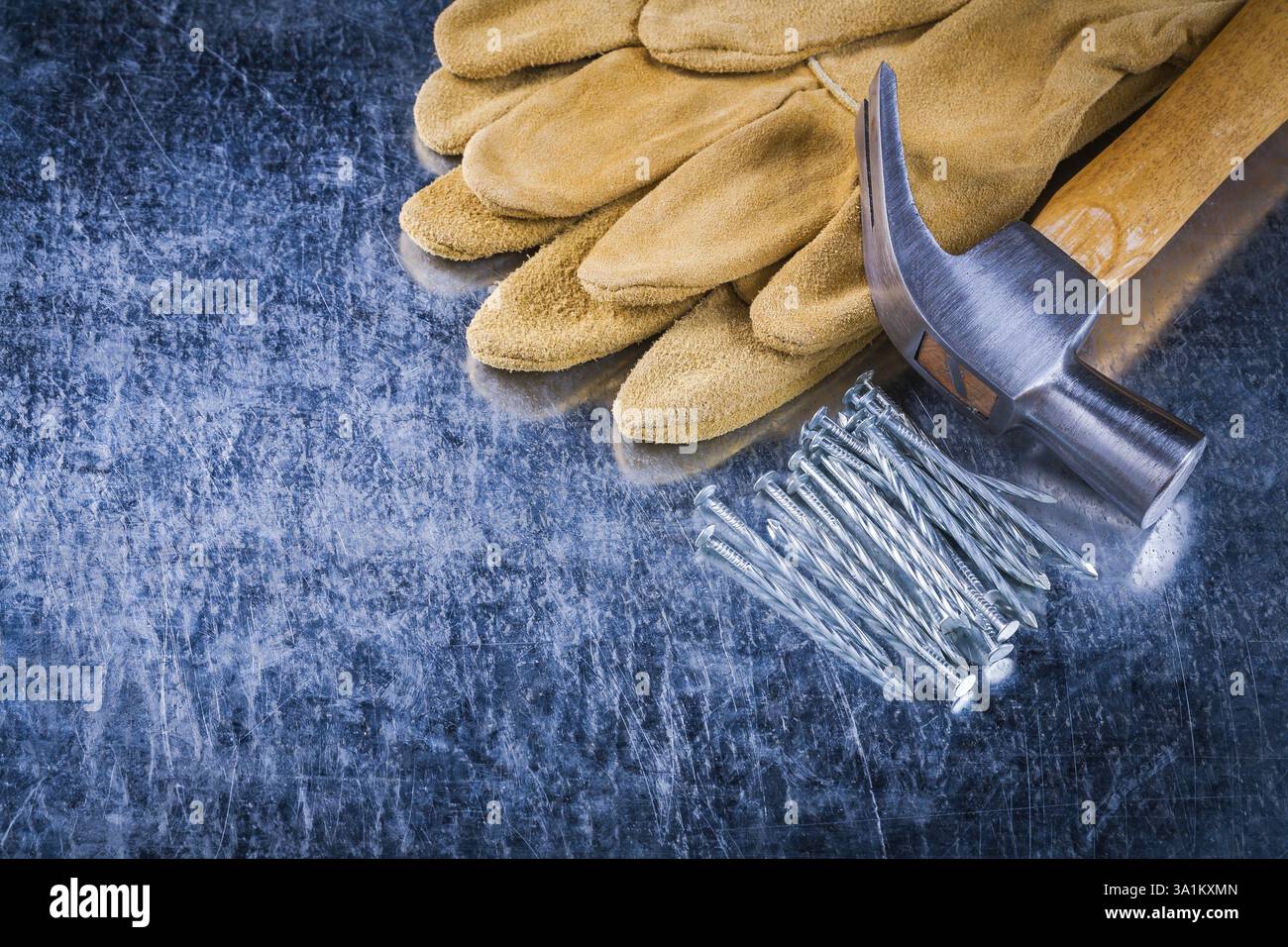 Paire de gants de sécurité en cuir clous de construction et marteau à griffe sur le concept de construction de fond métallique rayé Banque D'Images