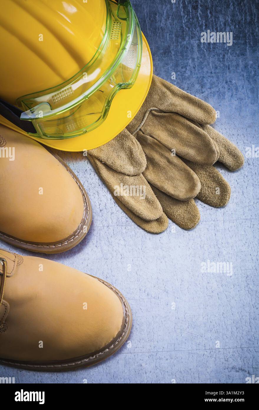 Paire de chaussures en dentelle de sécurité marron gants en cuir casque et lunettes de travail sur fond métallique rayé concept de construction Banque D'Images