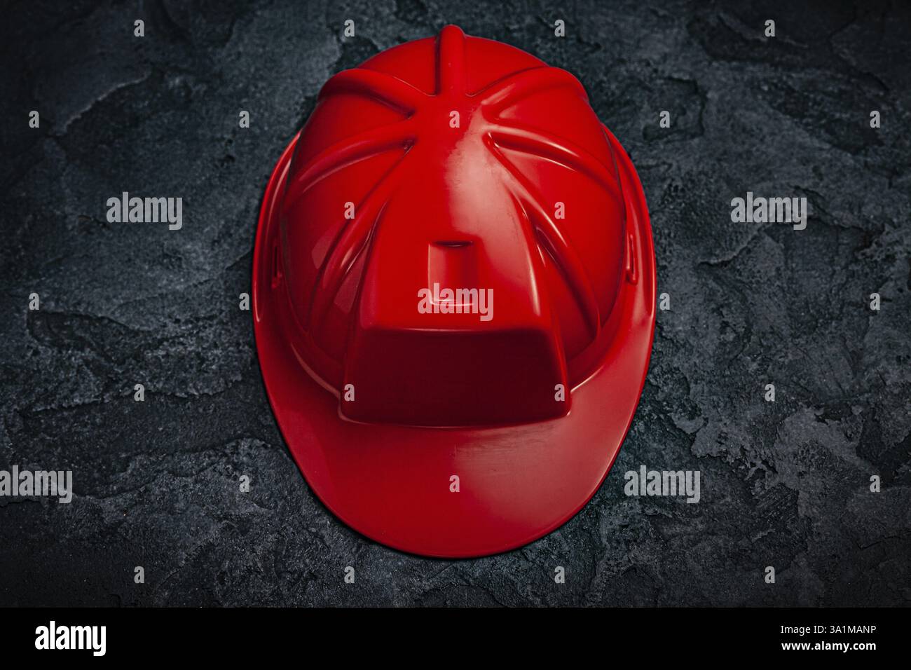 Casque de construction rouge sur fond de pierre sombre Banque D'Images