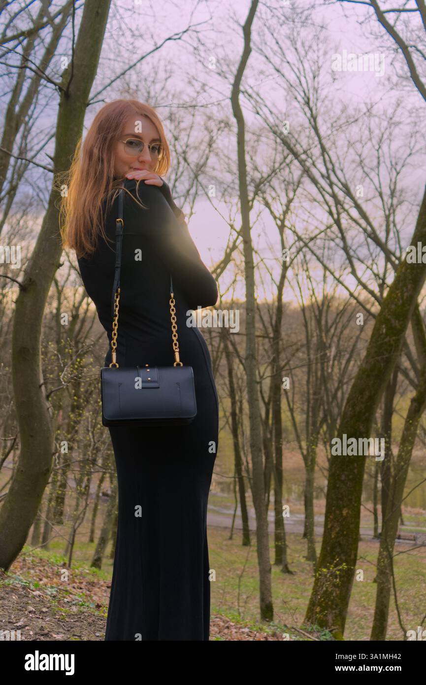 Une fille vêtue d'une robe noire se tient dans le parc Banque D'Images