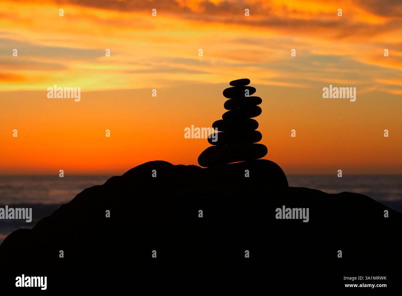 Beau symbole harmonieux de pierres empilées avec coucher de soleil coloré évoquent le calme et l'équilibre à la plage de la côte Pacifique à Cambria, Californie Banque D'Images