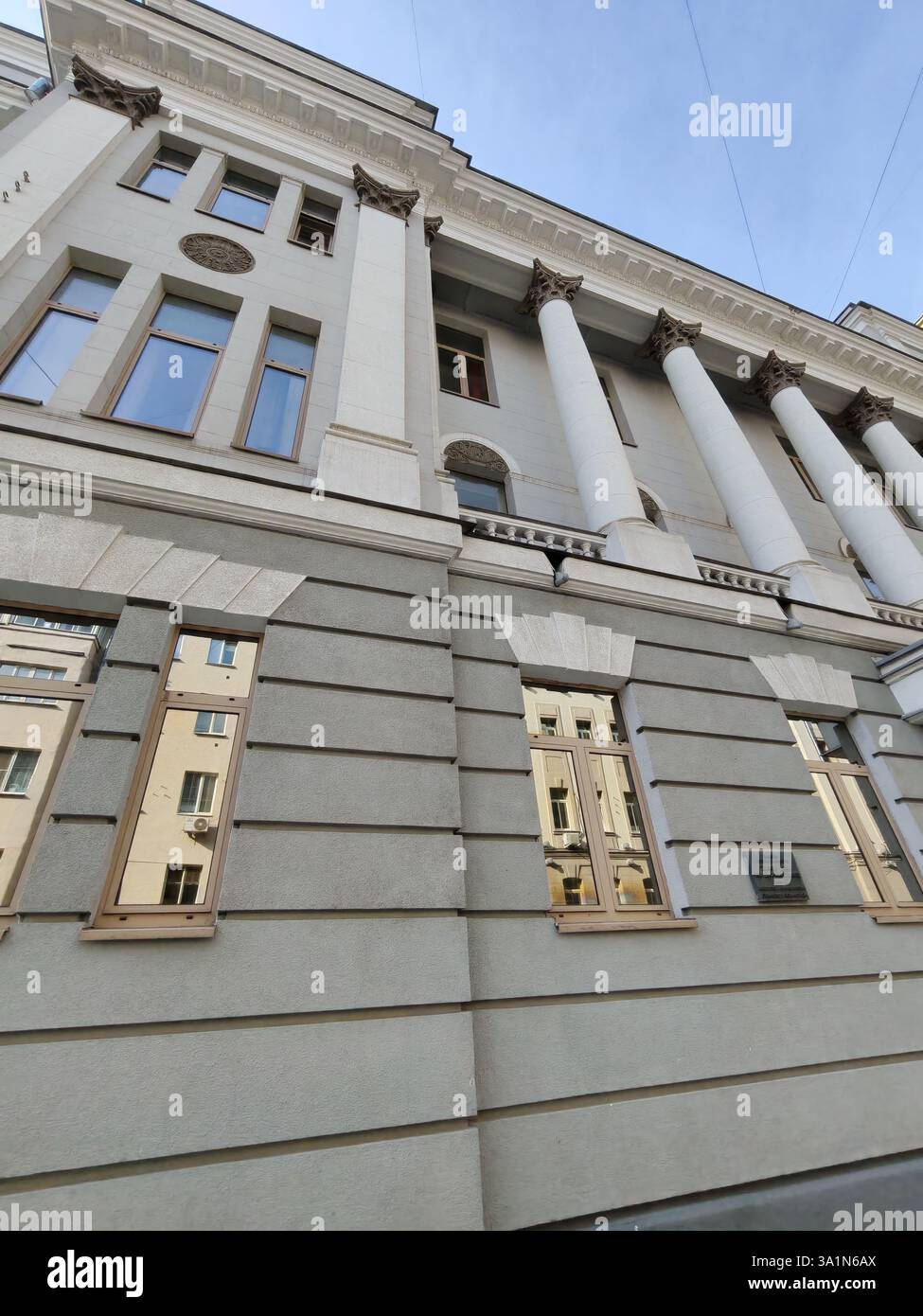 Un imposant bâtiment néoclassique avec des piliers blancs proéminents, des chapiteaux complexes et des murs gris lisses. L'image capture la beauté du classique Banque D'Images