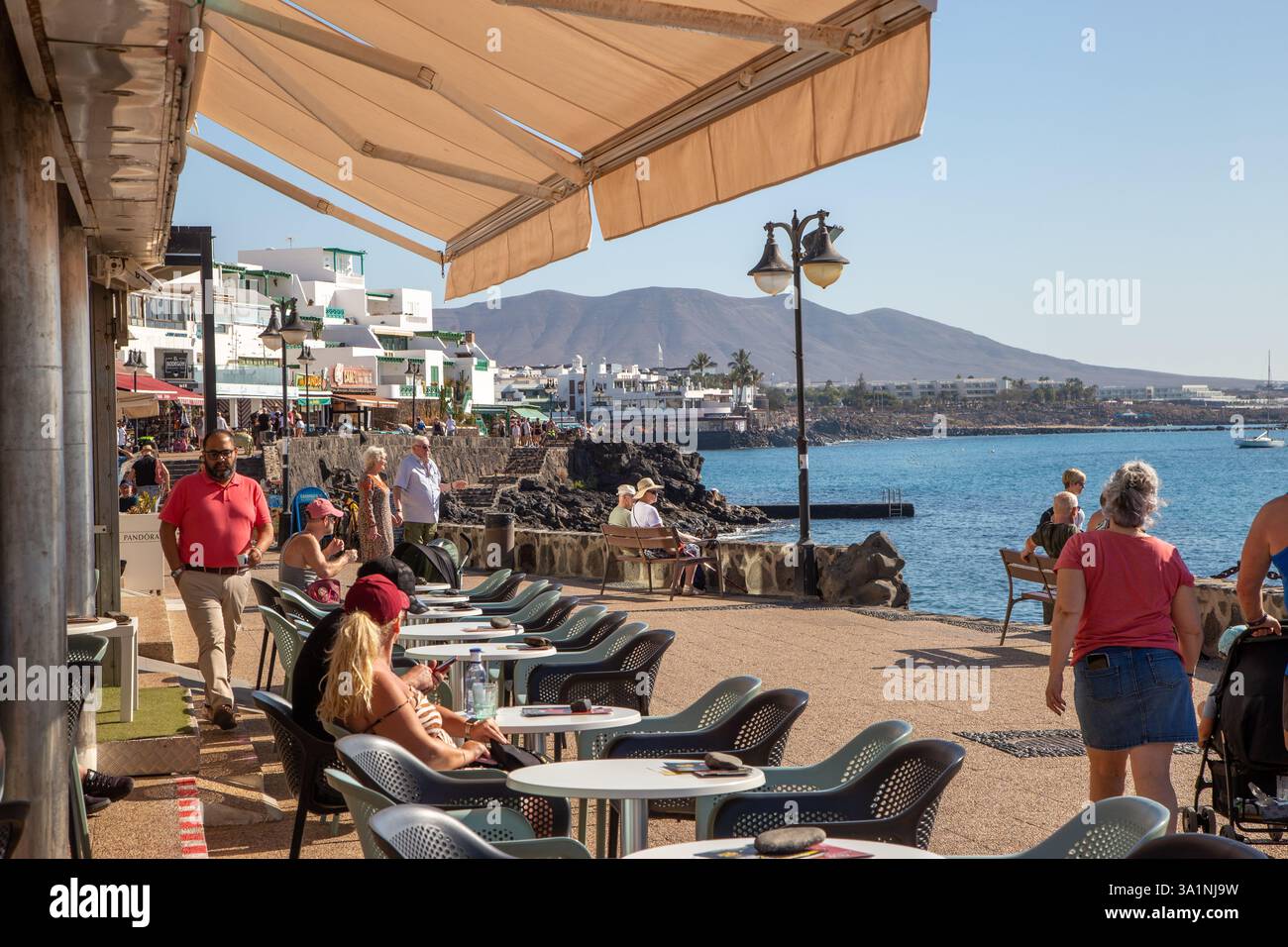 Les gens apprécient le soleil d'hiver de février dans les bars et cafés le long du port de la station balnéaire des Canaries de Playa Blanca Lanzarote Espagne Banque D'Images