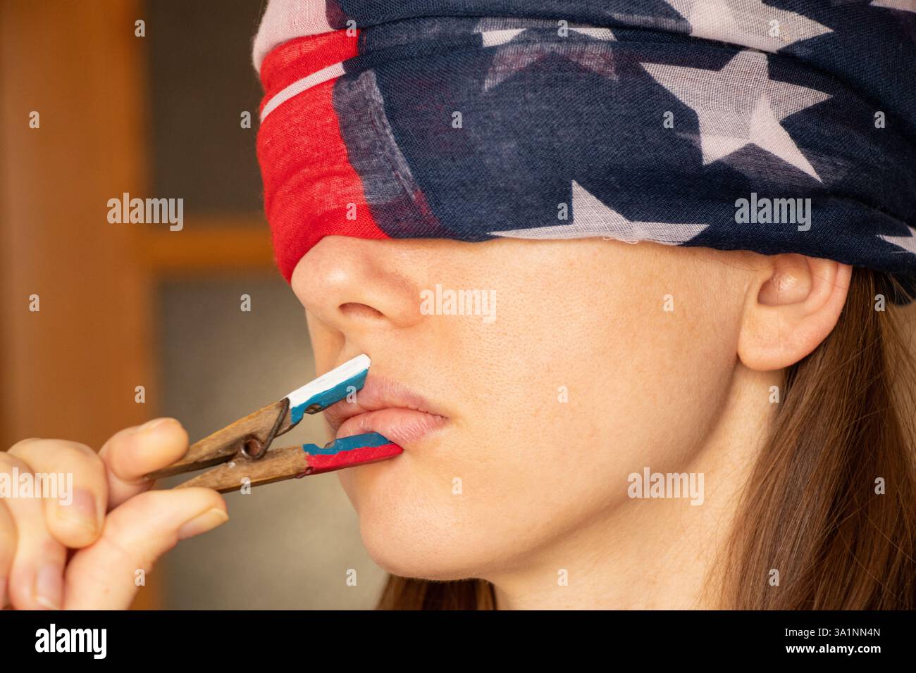 Fille couvre sa bouche avec une pince à linge avec un drapeau russe et un drapeau américain peint sur ses yeux, suppression des droits de vote, être trompé et Banque D'Images