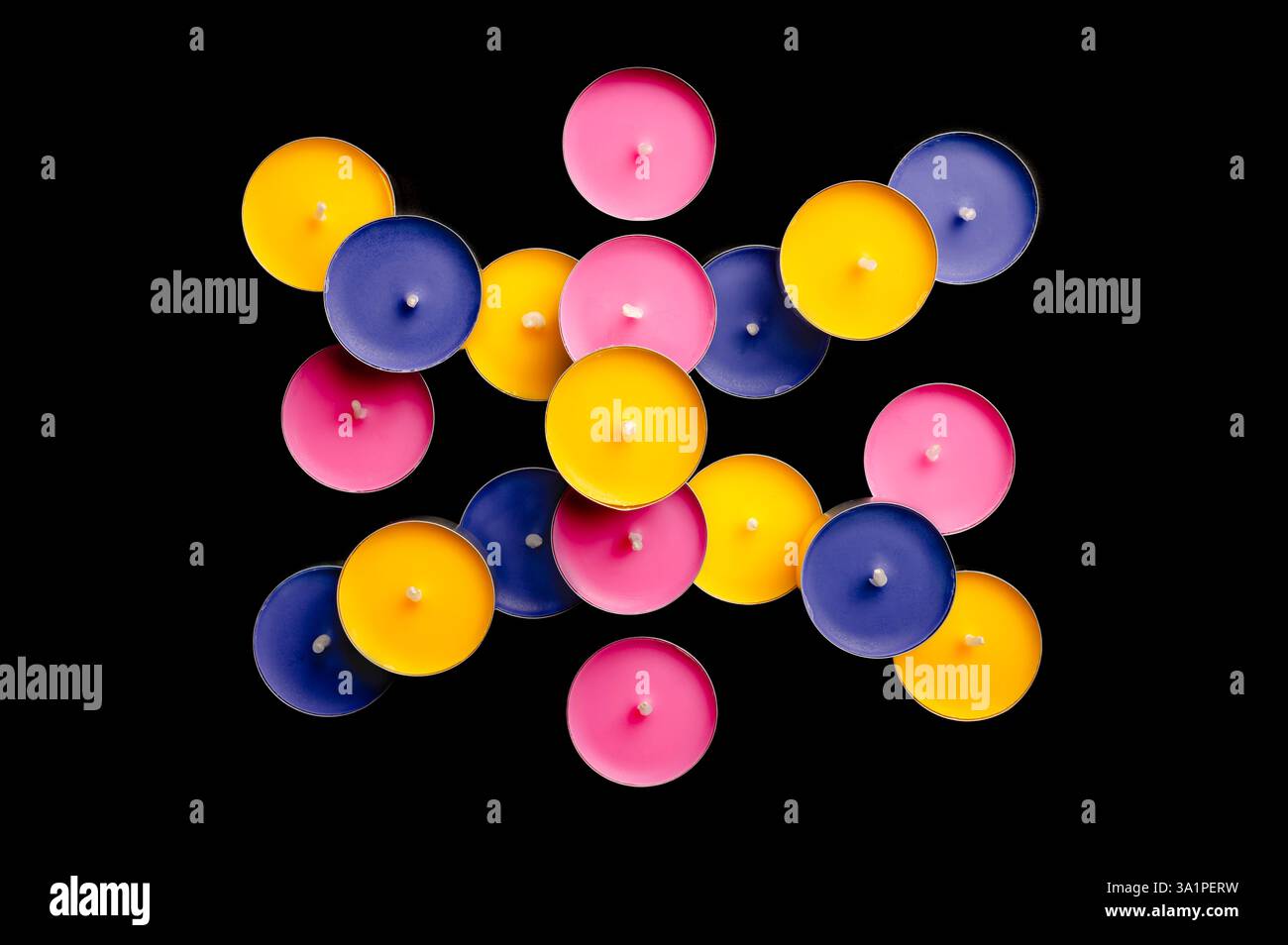 Lumières de thé en rose, jaune et bleu, disposées dans une composition ludique sur un fond noir dur. Banque D'Images