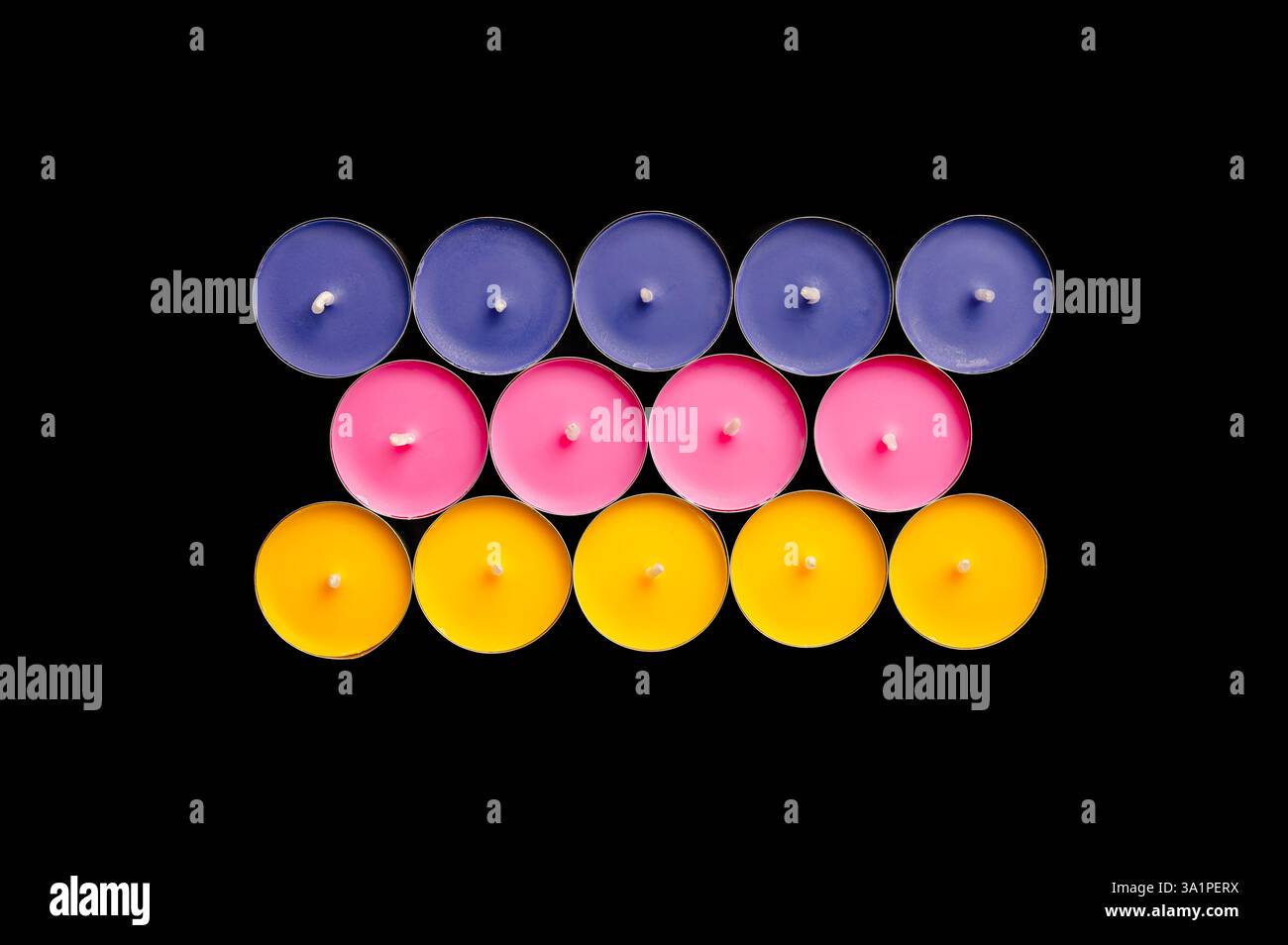 Lumières de thé en rose, jaune et bleu, disposées dans une composition ludique sur un fond noir dur. Banque D'Images