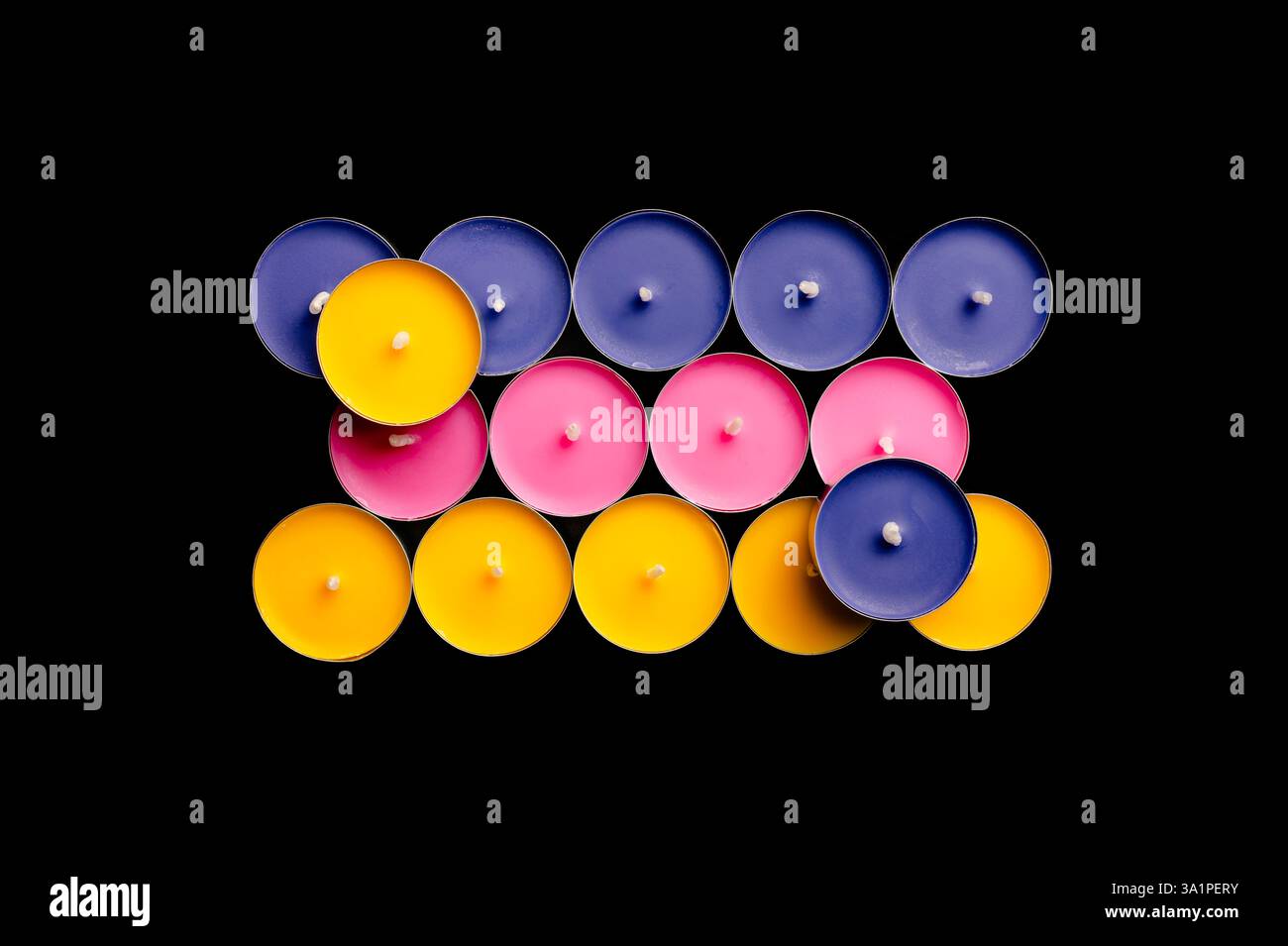Lumières de thé en rose, jaune et bleu, disposées dans une composition ludique sur un fond noir dur. Banque D'Images