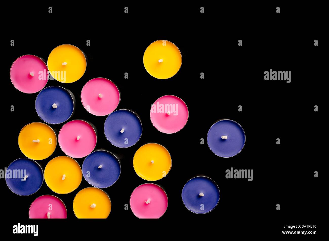 Lumières de thé en rose, jaune et bleu, disposées dans une composition ludique sur un fond noir dur. Banque D'Images