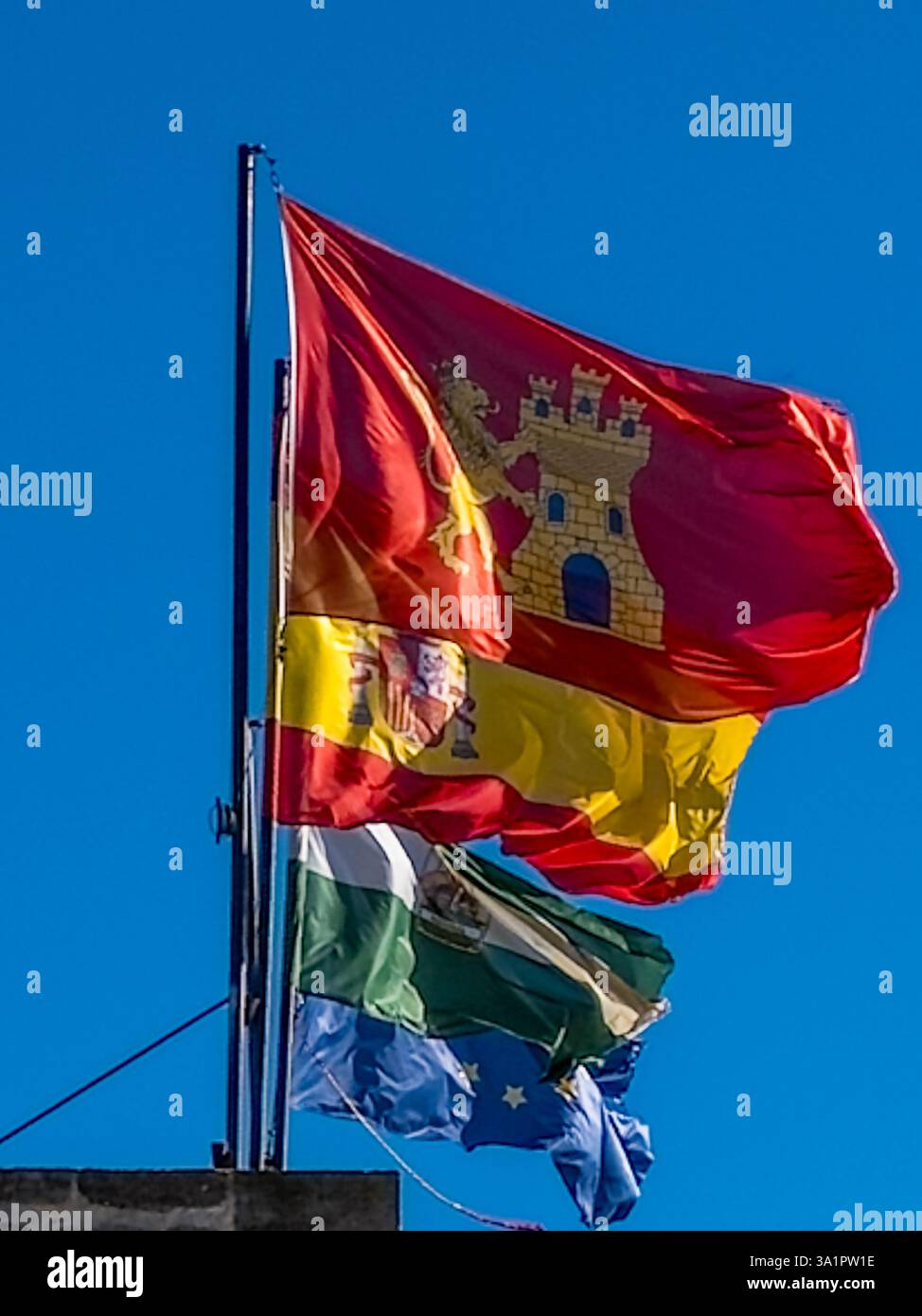 Drapeau rouge Alora avec château jaune vole à côté des drapeaux espagnol, andalou et UE sur fond bleu ciel Banque D'Images