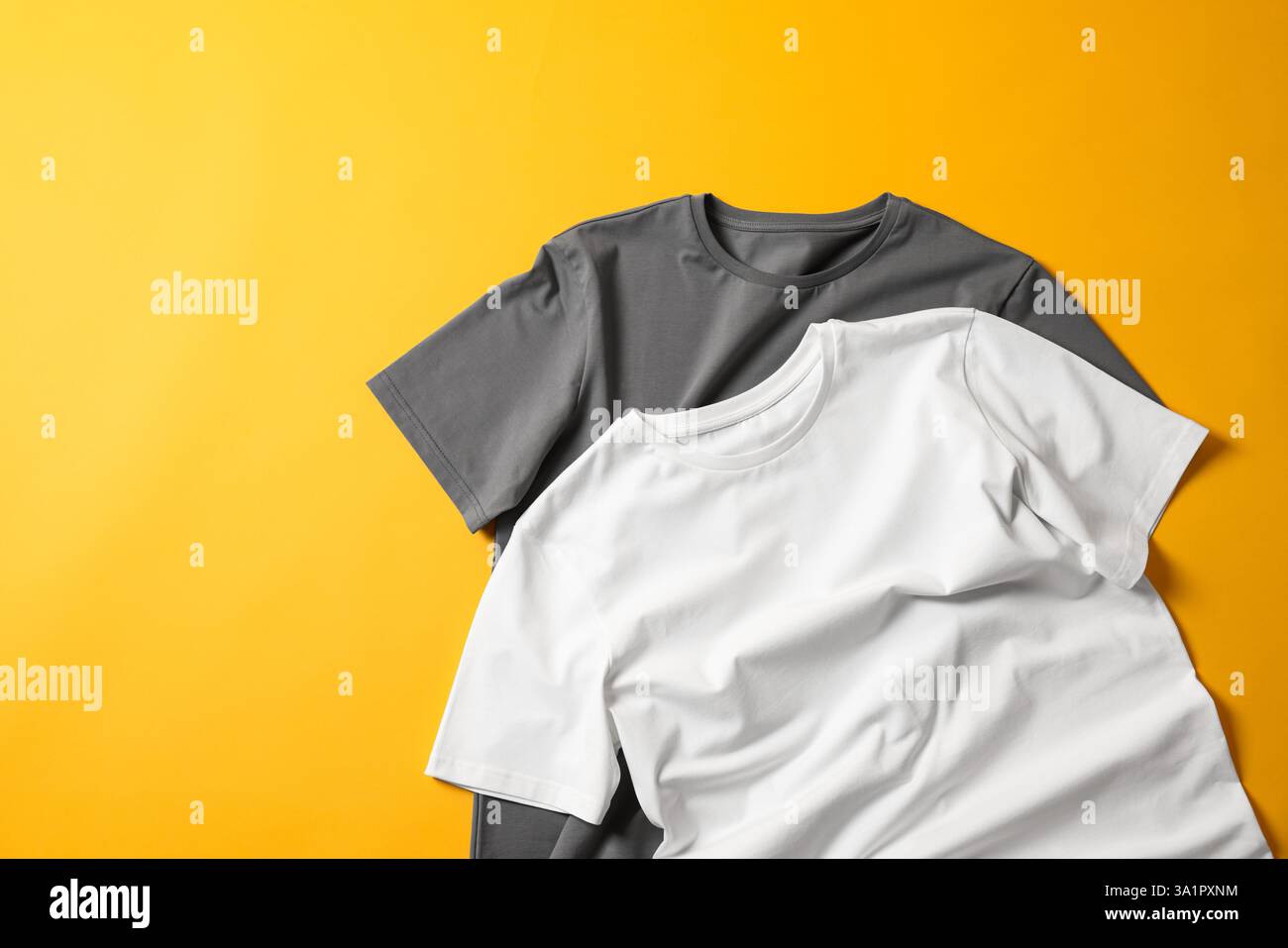 T-shirts vierges sur fond jaune, pose à plat. Maquette pour le design Banque D'Images T-shirts vierges sur fond jaune, pose à plat. Maquette pour le design Banque D'Images