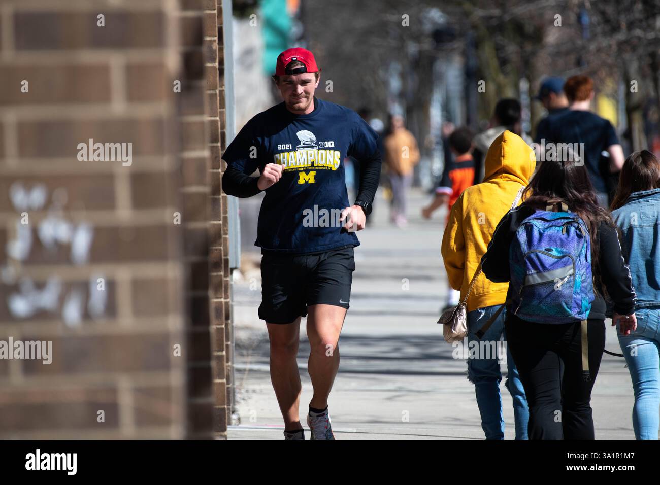 Ann Arbor, Michigan, États-Unis. 9 mars 2025. Un homme fait du jogging dans le centre-ville d'Ann Arbor par une journée ensoleillée. (Crédit image : © Mark Bialek/ZUMA Press Wire) USAGE ÉDITORIAL SEULEMENT! Non destiné à UN USAGE commercial ! Banque D'Images