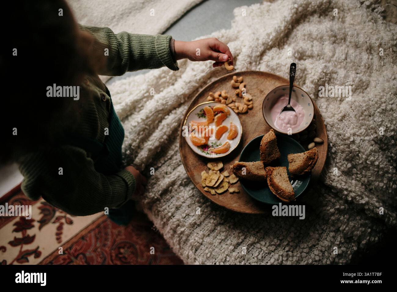 Plateau de petit déjeuner confortable avec yaourt, pain et fruits sur une couverture moelleuse Banque D'Images Plateau de petit déjeuner confortable avec yaourt, pain et fruits sur une couverture moelleuse Banque D'Images