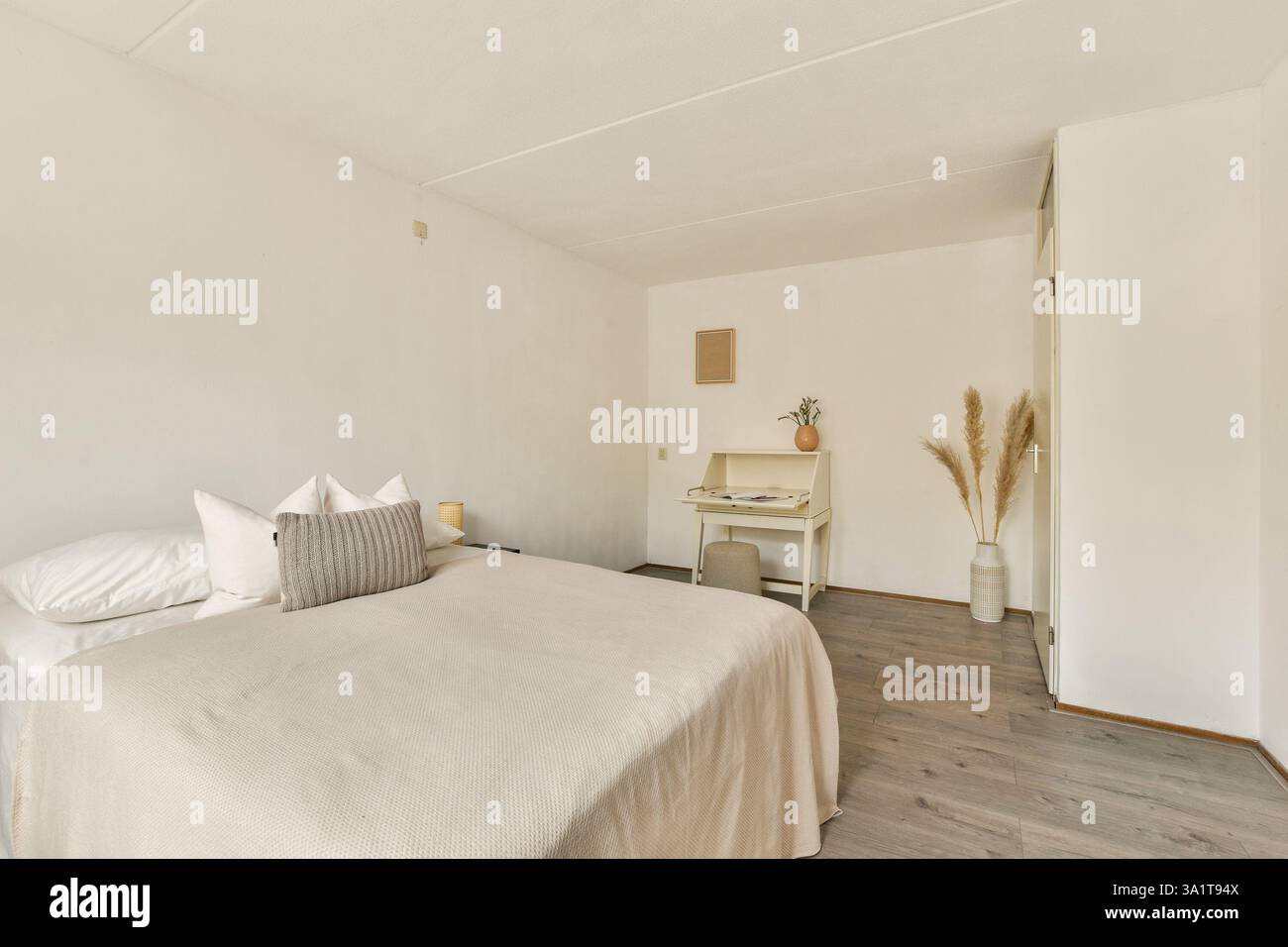 Une chambre lumineuse et aérée avec un décor minimaliste, un lit confortable et un mobilier élégant, parfait pour la détente et la tranquillité. Banque D'Images