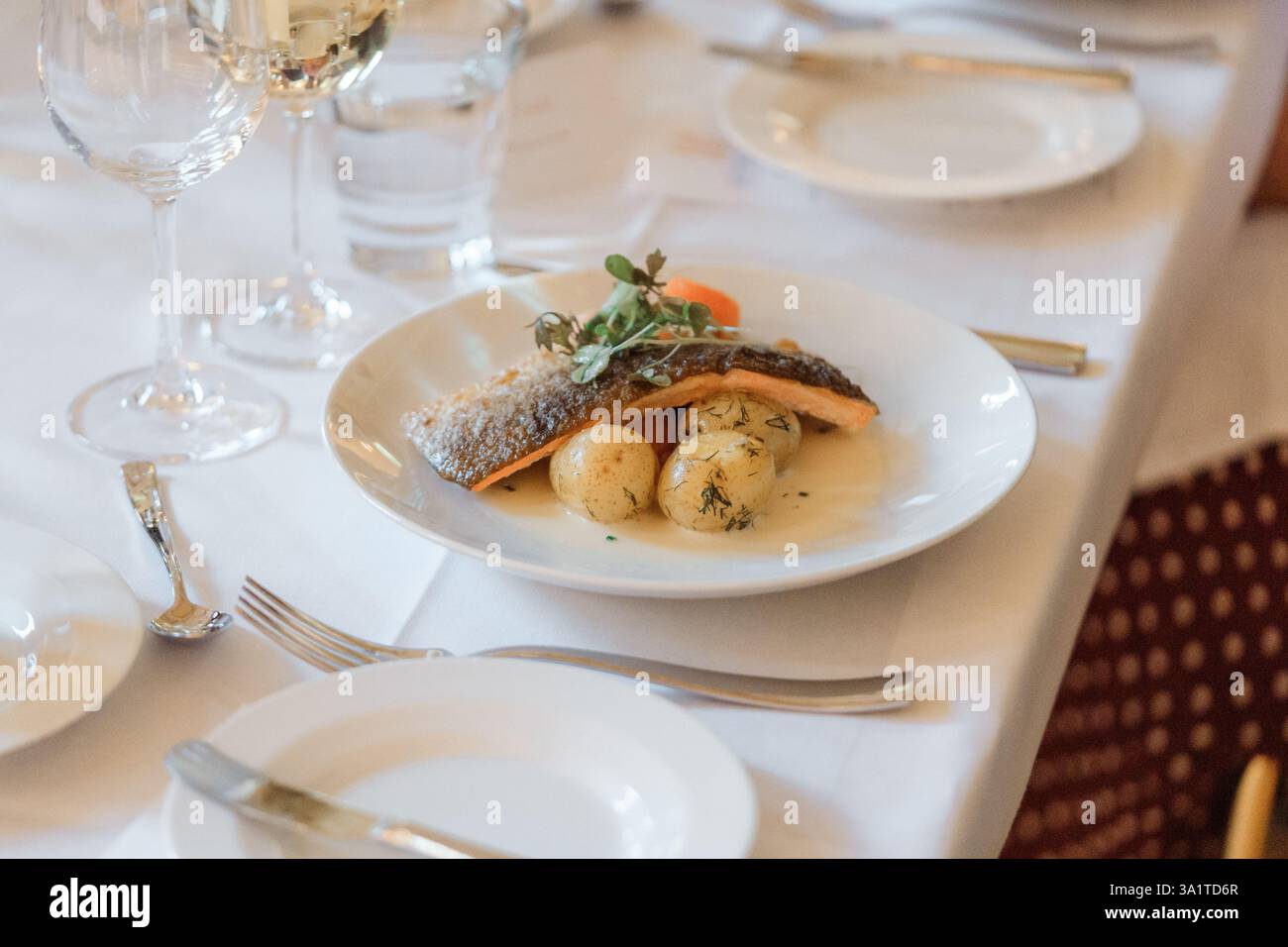 Filet de poisson avec pommes de terre et herbes sur une assiette blanche dans un restaurant Banque D'Images